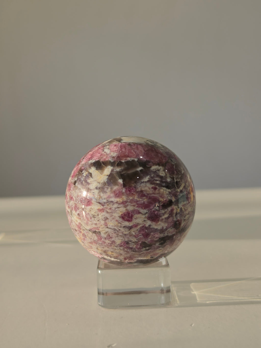 Luxury Pink Tourmaline Sphere by Stone and Bloom featuring rich raspberry and blush tones with intricate natural mineral formations
