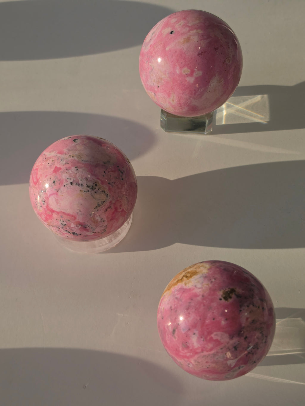High quality Peruvian Pink Rhodonite crystal sphere with rich pink mineral patterns and elegant statement décor styling curated by Stone and Bloom.