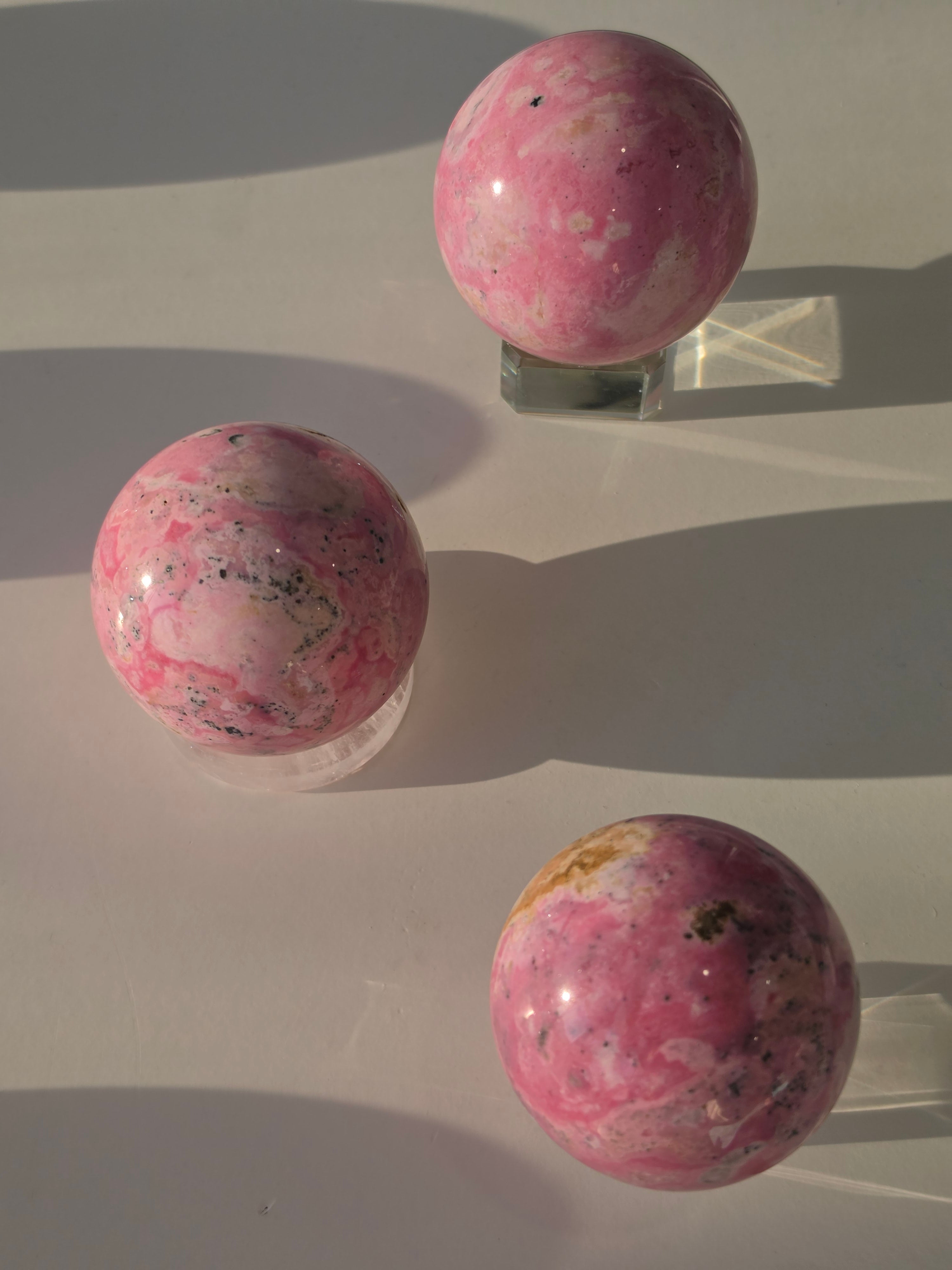 High quality Peruvian Pink Rhodonite crystal sphere with rich pink mineral patterns and elegant statement décor styling curated by Stone and Bloom.