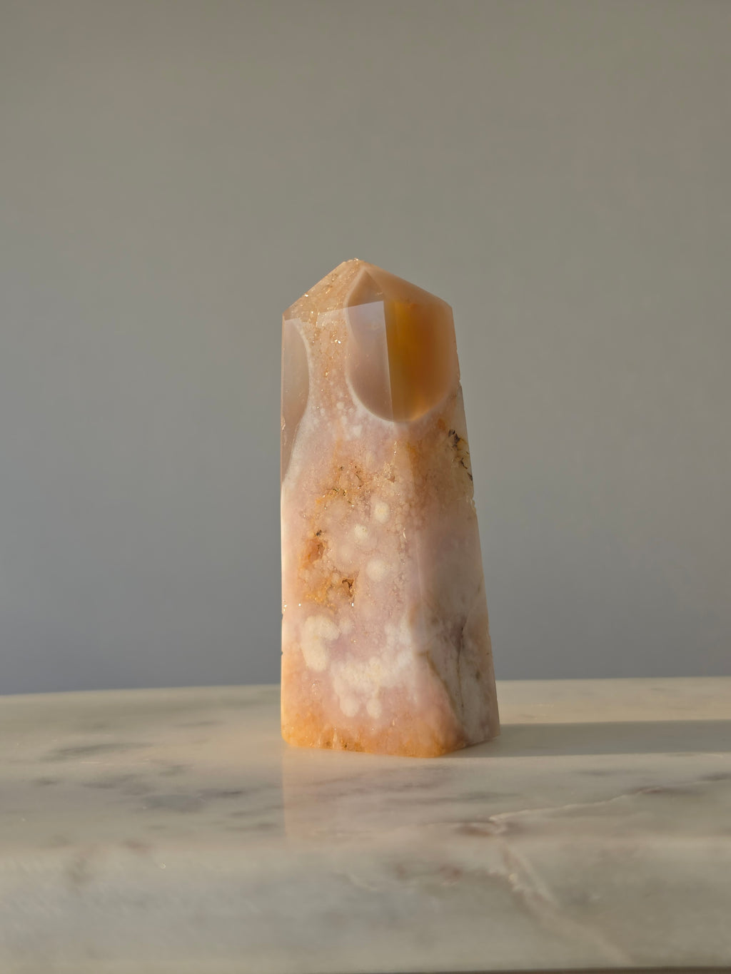 High-grade Pink Amethyst crystal tower featuring soft blush pink tones, sparkling druzy crystal formations, natural crystalline pockets, and polished geometric facets, photographed in natural light.