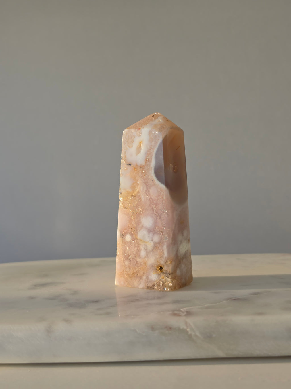 High-grade Pink Amethyst crystal tower featuring soft blush pink tones, sparkling druzy crystal formations, natural crystalline pockets, and polished geometric facets, photographed in natural light.
