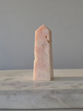 High-grade Pink Amethyst crystal tower featuring soft blush pink tones, sparkling druzy crystal formations, natural crystalline pockets, and polished geometric facets, photographed in natural light.