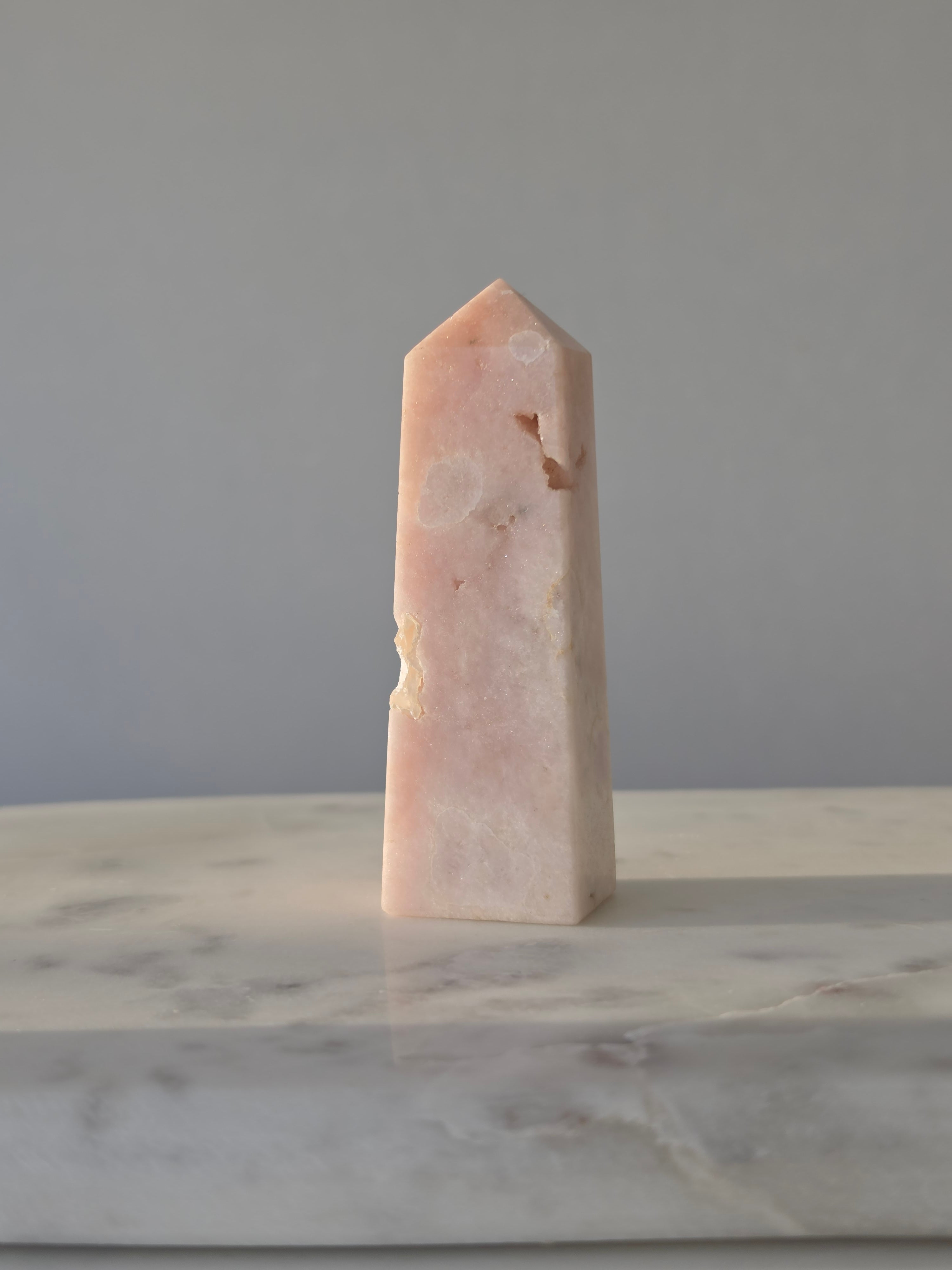 High-grade Pink Amethyst crystal tower featuring soft blush pink tones, sparkling druzy crystal formations, natural crystalline pockets, and polished geometric facets, photographed in natural light.