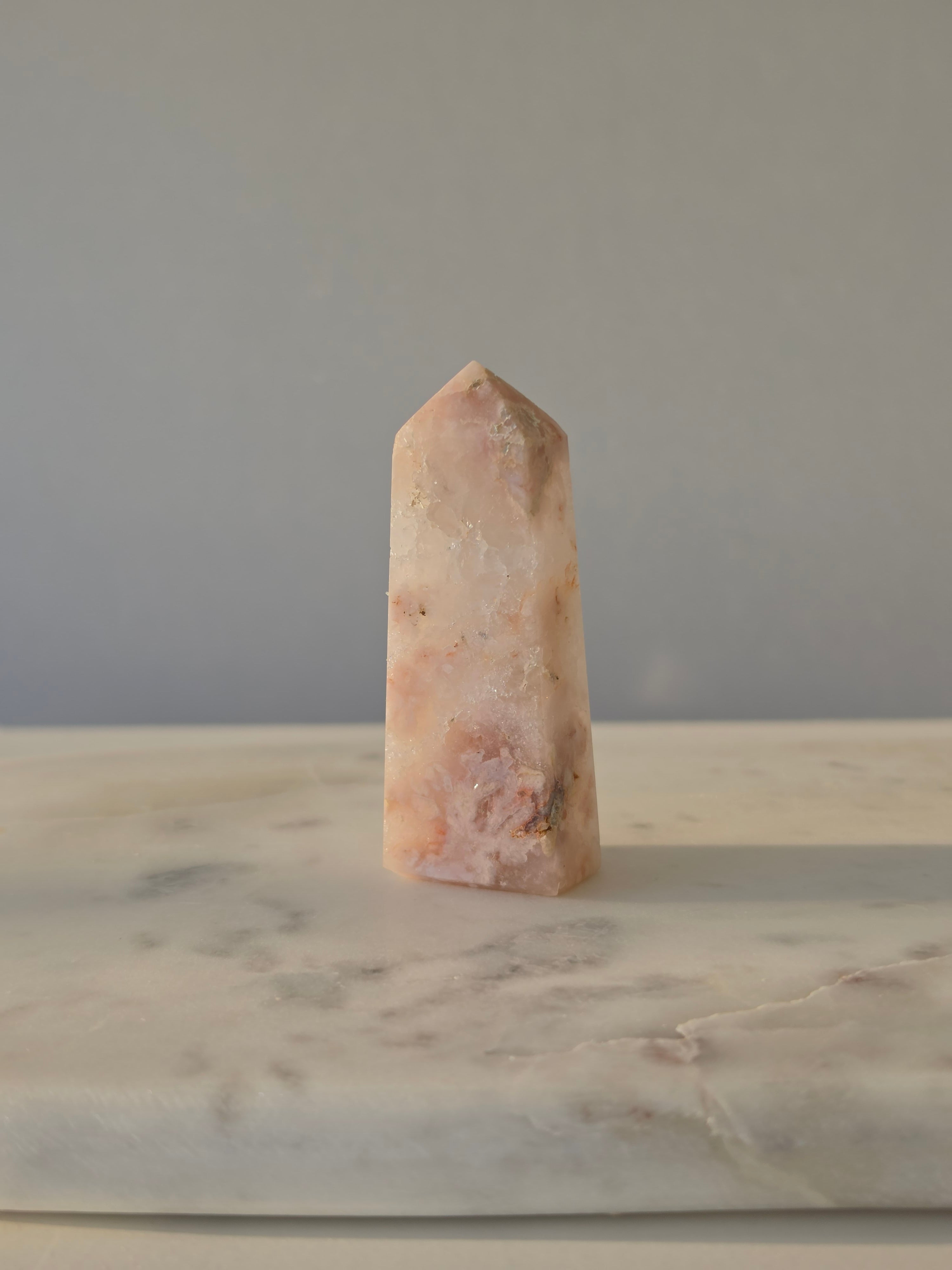 High-grade Pink Amethyst crystal tower featuring soft blush pink tones, sparkling druzy crystal formations, natural crystalline pockets, and polished geometric facets, photographed in natural light.
