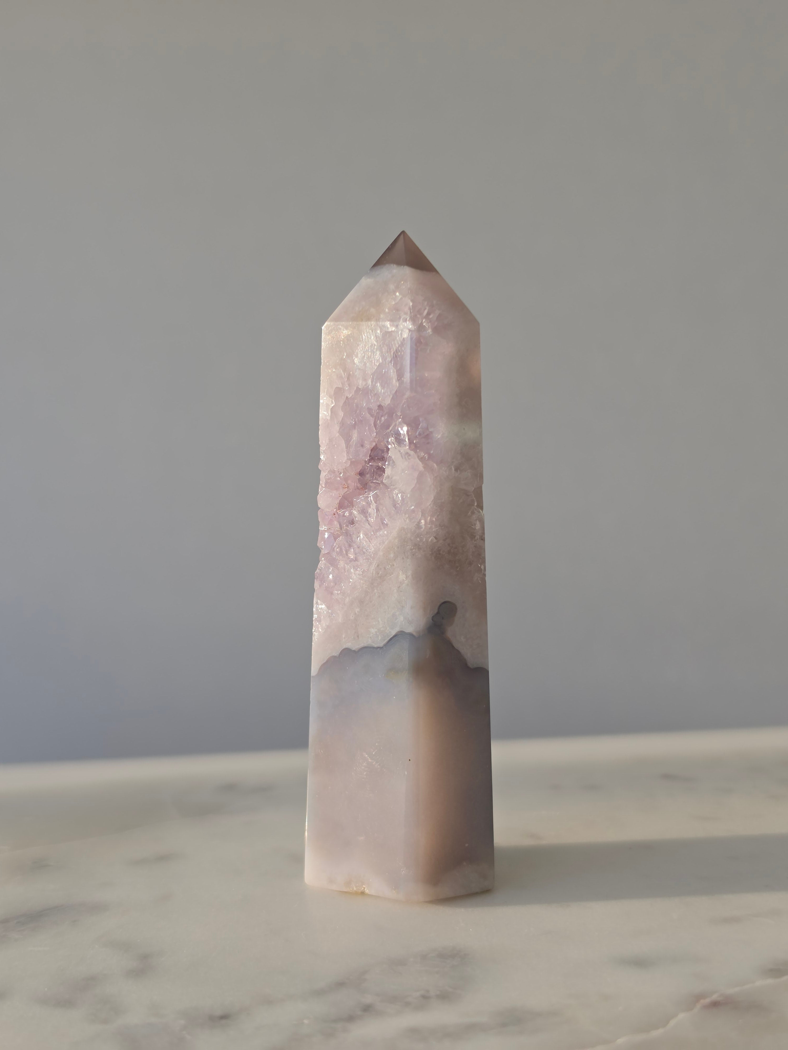 High-grade Purple Amethyst druzy tower featuring soft lavender crystal formations, sparkling druzy pocket, natural agate banding, and polished geometric facets, photographed in natural light.
