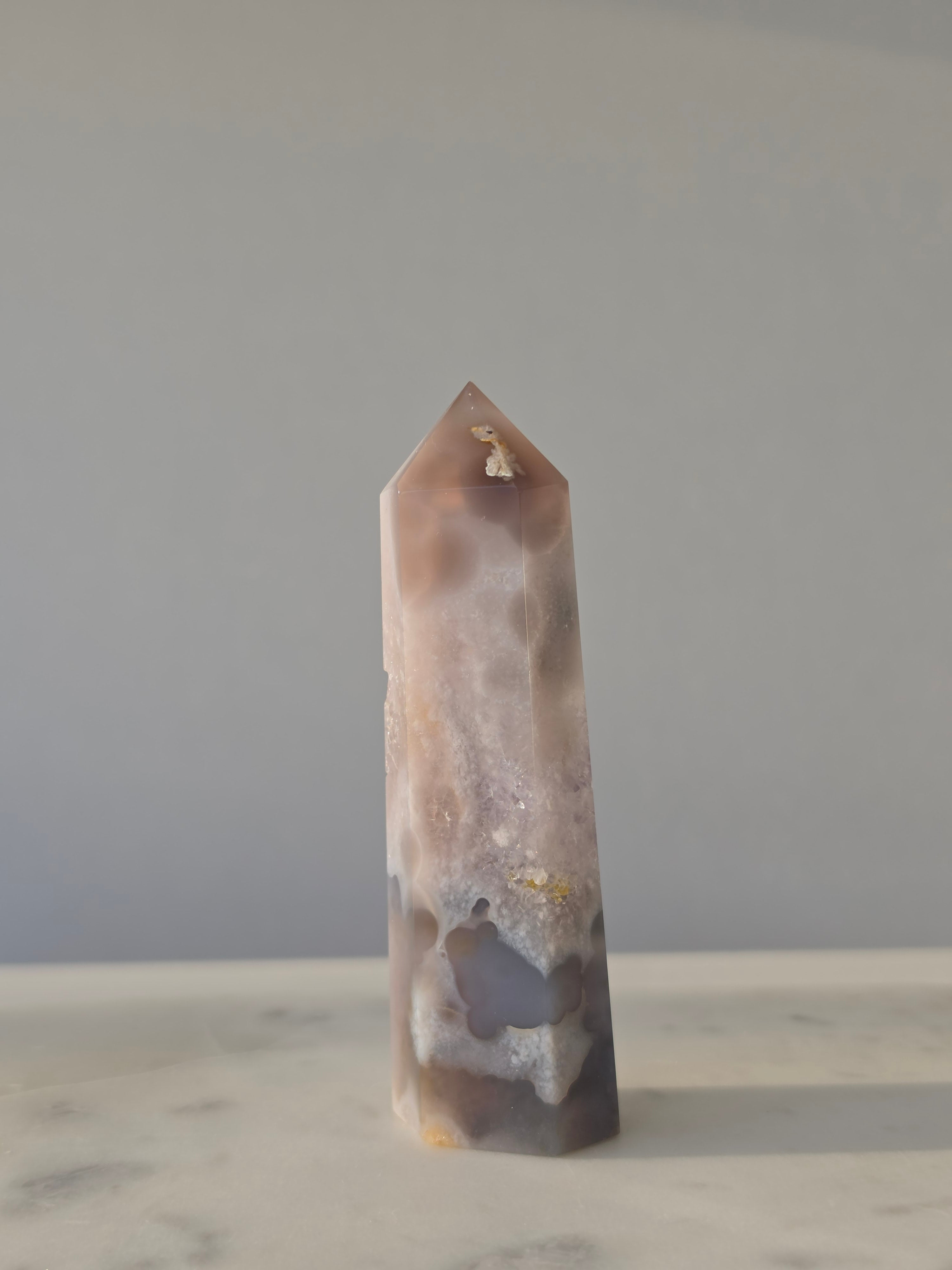 High-grade Purple Amethyst druzy tower featuring soft lavender crystal formations, sparkling druzy pocket, natural agate banding, and polished geometric facets, photographed in natural light.