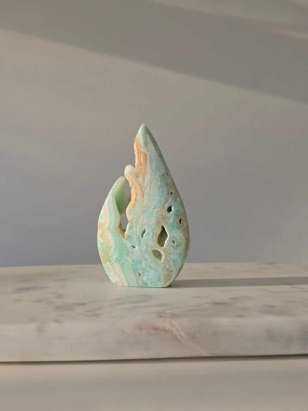 High-grade Hemimorphite flame featuring oceanic aqua and seafoam green banding, natural sculptural cavities, and flowing mineral patterns, photographed in natural light and curated by Stone and Bloom.