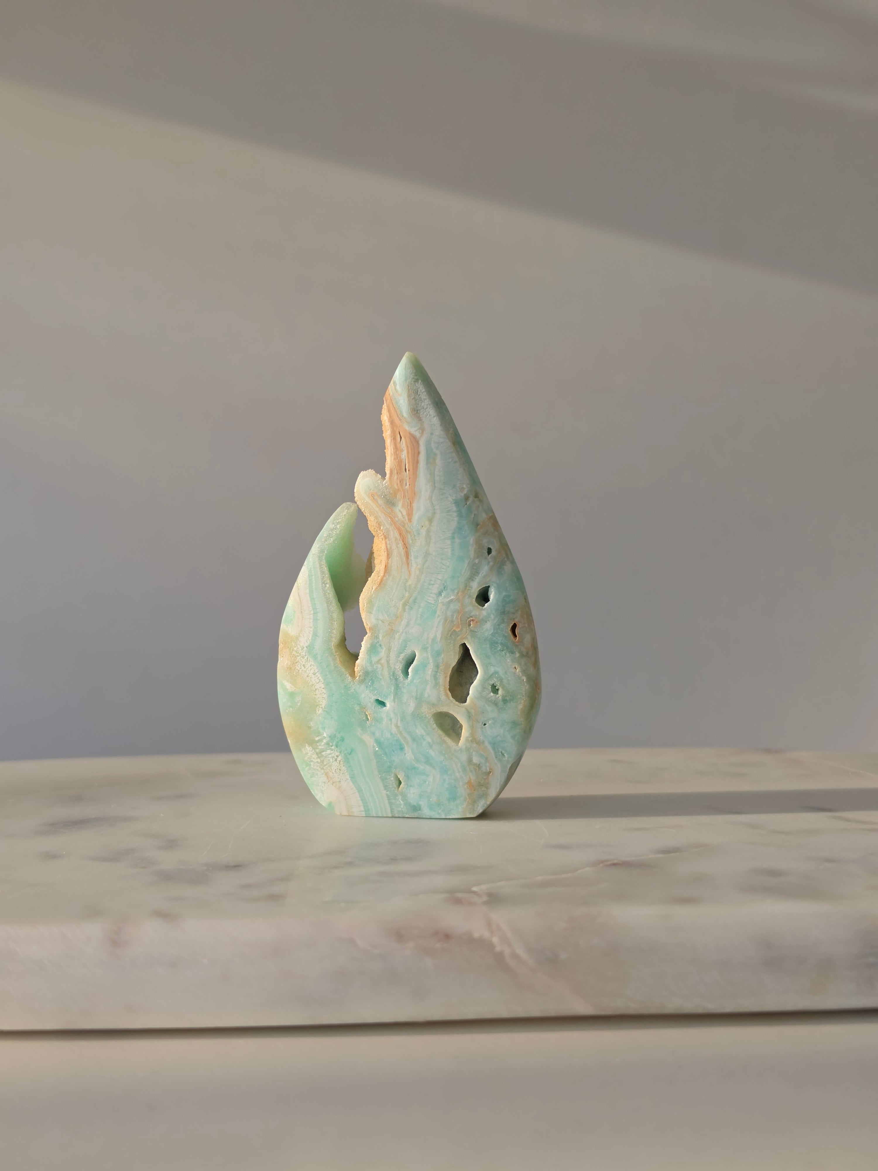 High-grade Hemimorphite flame featuring oceanic aqua and seafoam green banding, natural sculptural cavities, and flowing mineral patterns, photographed in natural light and curated by Stone and Bloom.