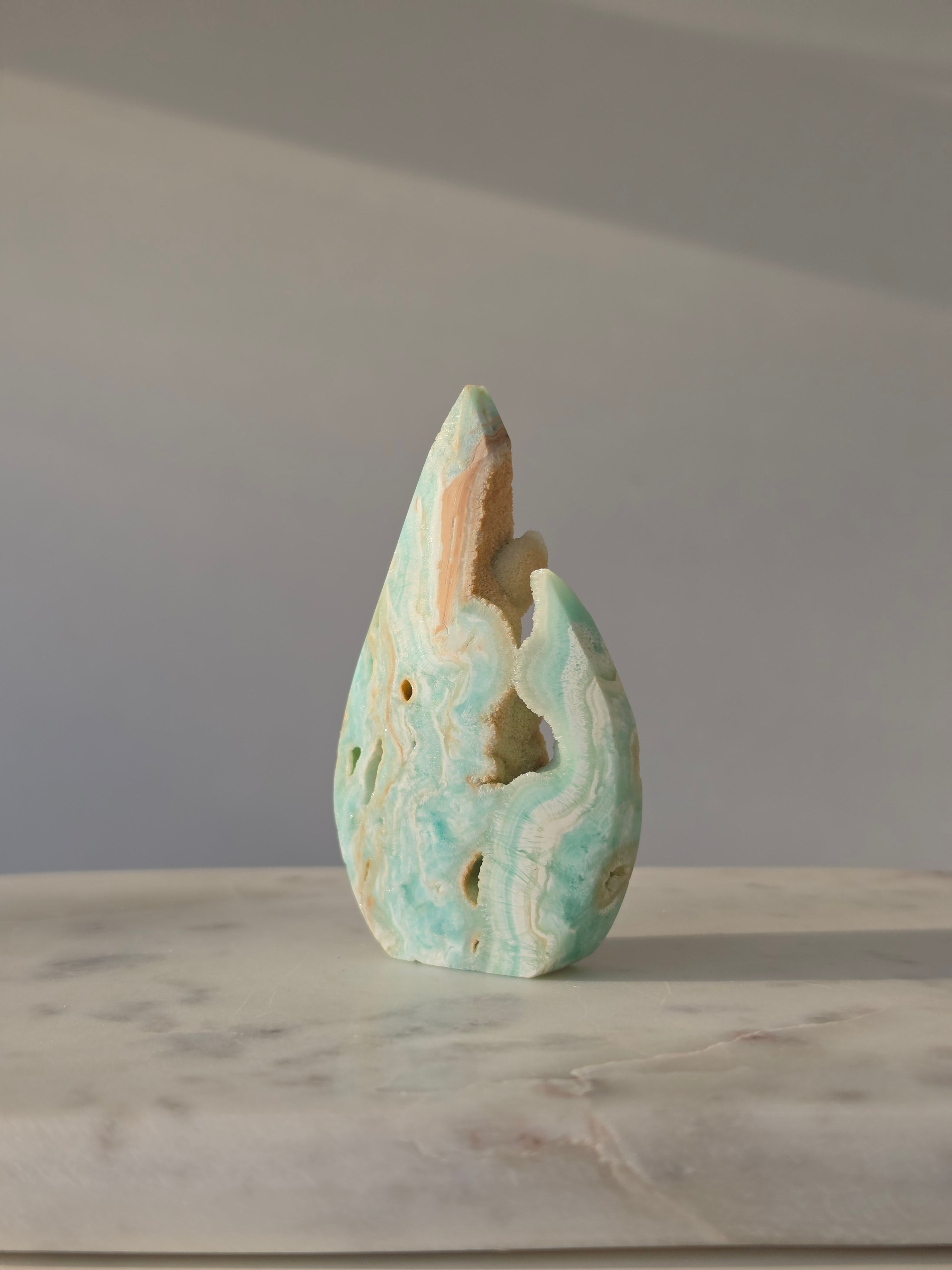 High-grade Hemimorphite flame featuring oceanic aqua and seafoam green banding, natural sculptural cavities, and flowing mineral patterns, photographed in natural light and curated by Stone and Bloom.