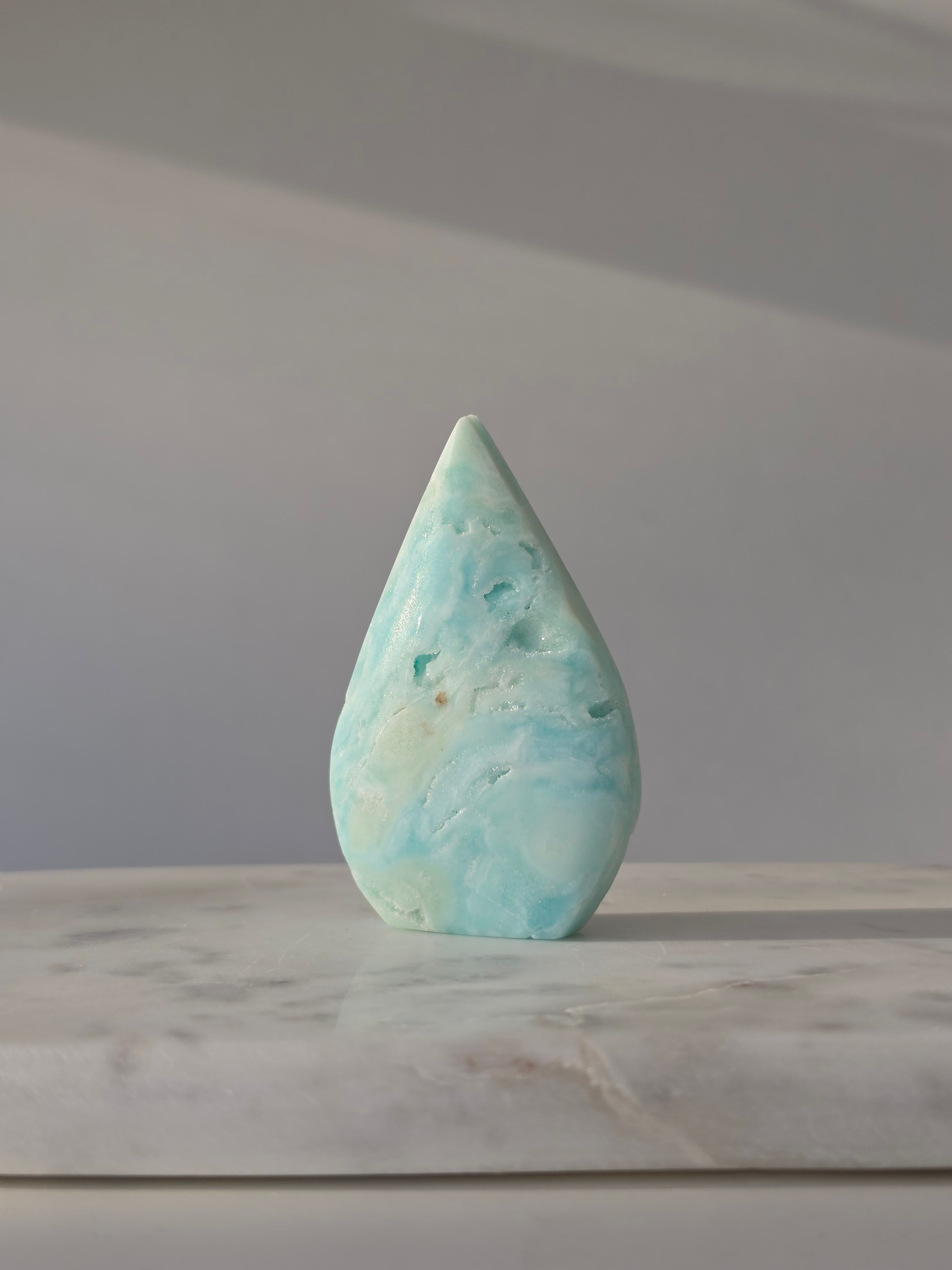 High-grade Hemimorphite flame featuring oceanic aqua and seafoam green banding, natural sculptural cavities, and flowing mineral patterns, photographed in natural light and curated by Stone and Bloom.