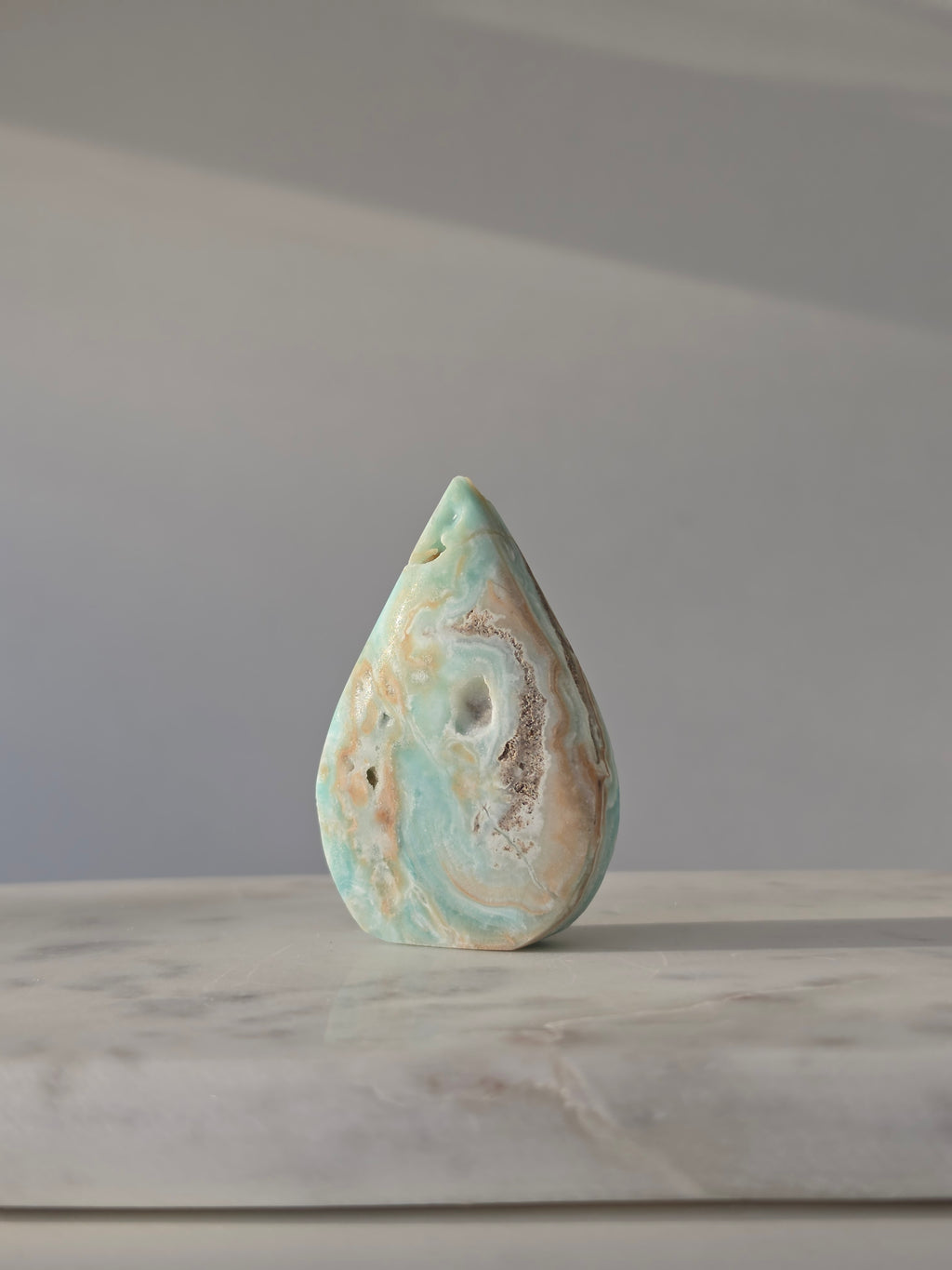 High-grade Hemimorphite flame featuring oceanic aqua and seafoam green banding, natural sculptural cavities, and flowing mineral patterns, photographed in natural light and curated by Stone and Bloom.