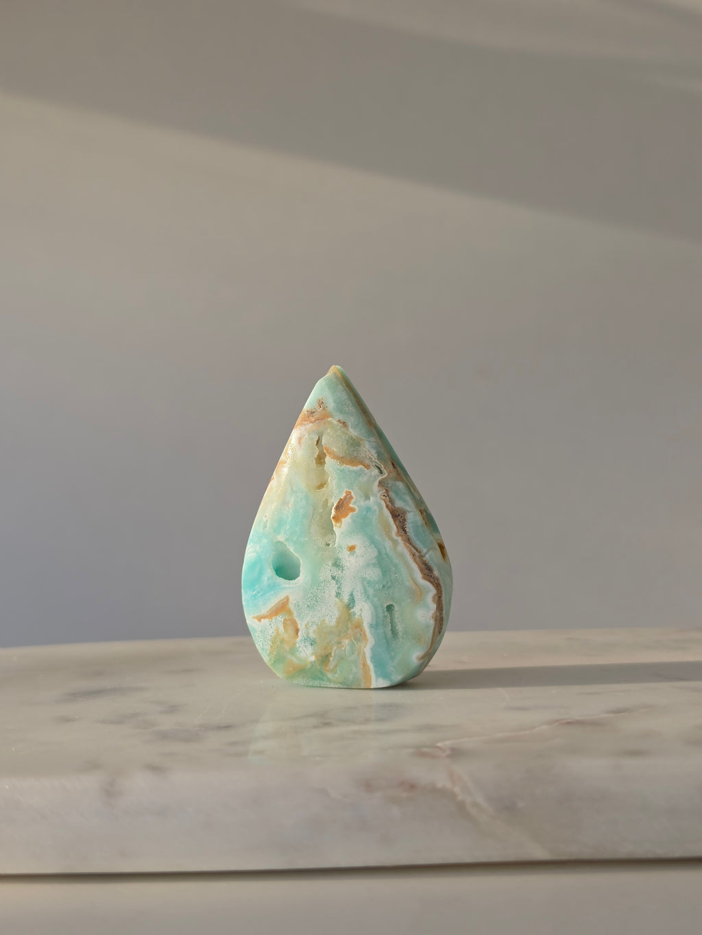 High-grade Hemimorphite flame featuring oceanic aqua and seafoam green banding, natural sculptural cavities, and flowing mineral patterns, photographed in natural light and curated by Stone and Bloom.