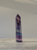 High-grade Rainbow Fluorite crystal tower featuring translucent aqua, mint green, and violet banding with natural internal rainbows and exceptional clarity, curated by Stone and Bloom.