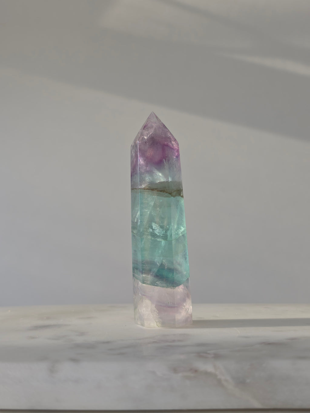 High-grade Rainbow Fluorite crystal tower featuring translucent aqua, mint green, and violet banding with natural internal rainbows and exceptional clarity, curated by Stone and Bloom.