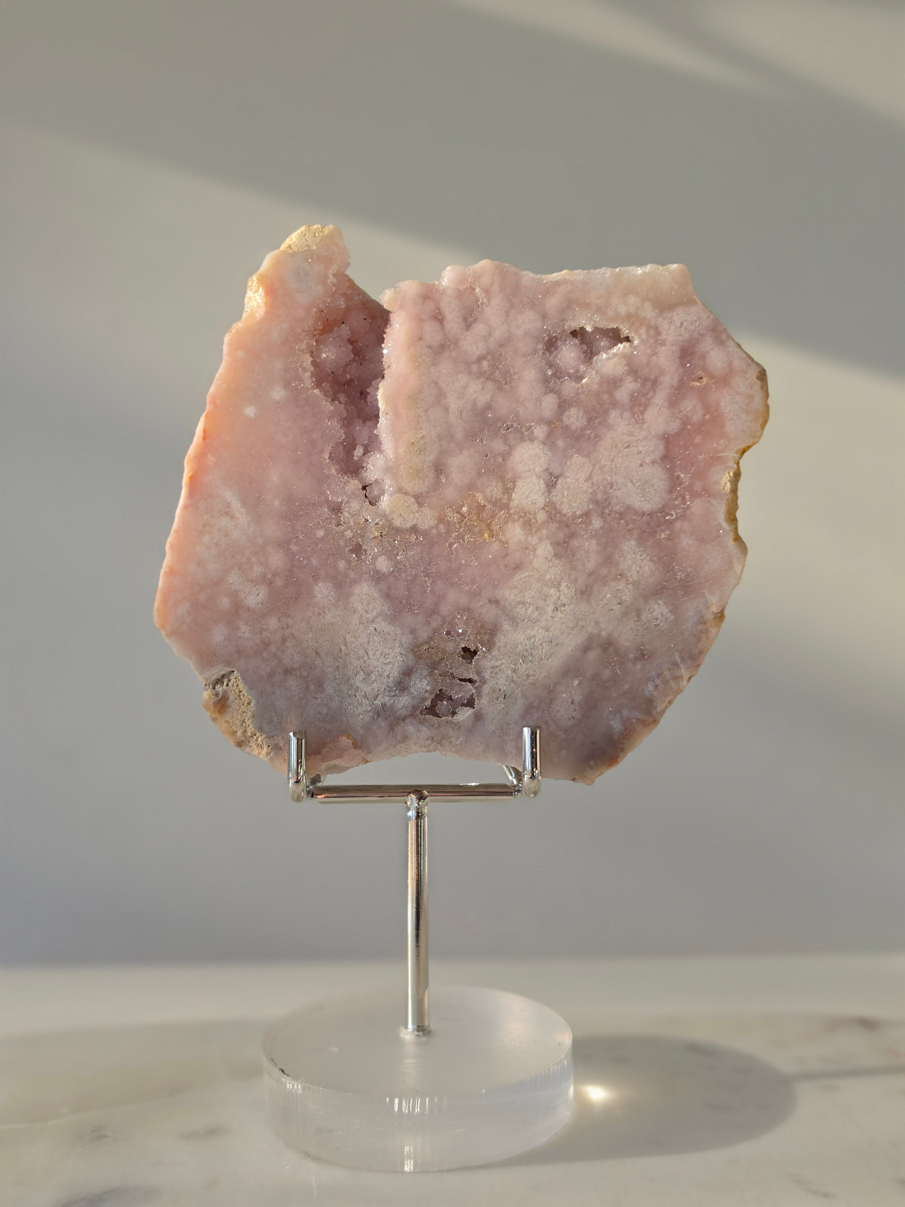 High-grade Pink Amethyst specimen on display stand featuring vibrant blush pink tones, sparkling druzy crystal formations, and natural crystalline pockets, curated by Stone and Bloom.