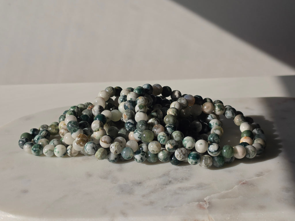 High-grade Moss Agate beaded bracelets featuring polished natural gemstones with rich forest green, soft ivory, and intricate moss-like inclusions, handcrafted with premium quality stones and photographed in natural light.