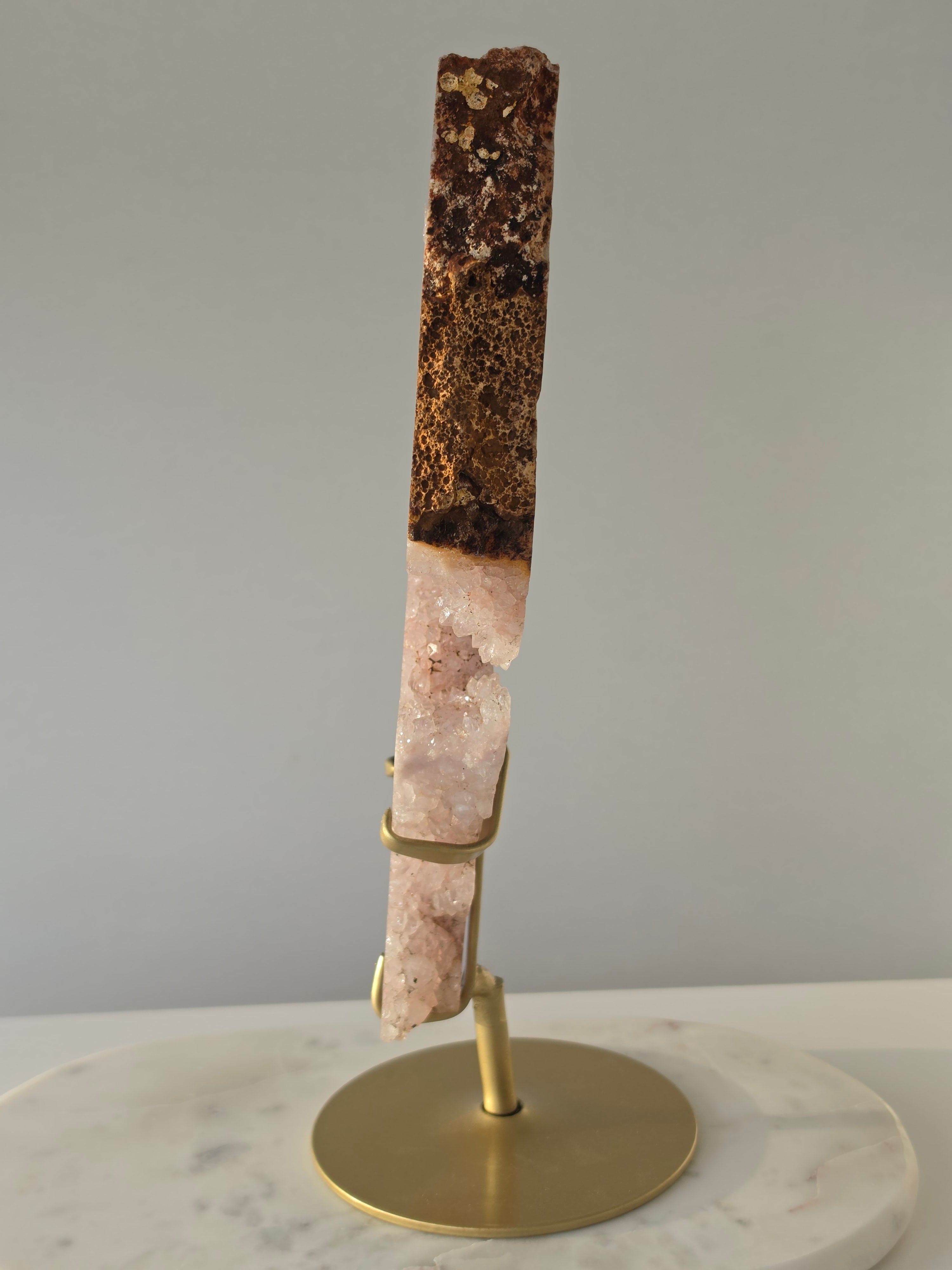 High-grade Brazilian Pink Amethyst slice on a gold display stand featuring sparkling blush-pink druzy crystals, natural agate banding, sculptural open formations, and delicate rose and champagne tones, photographed in natural light