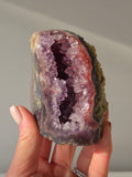 High-grade Brazilian Pink Amethyst cut base featuring a sparkling druzy crystal cavern, soft blush and lavender crystal points, natural agate banding in charcoal and rose tones, polished free-standing edges, and sourced from Rio Grande do Sul, Brazil.