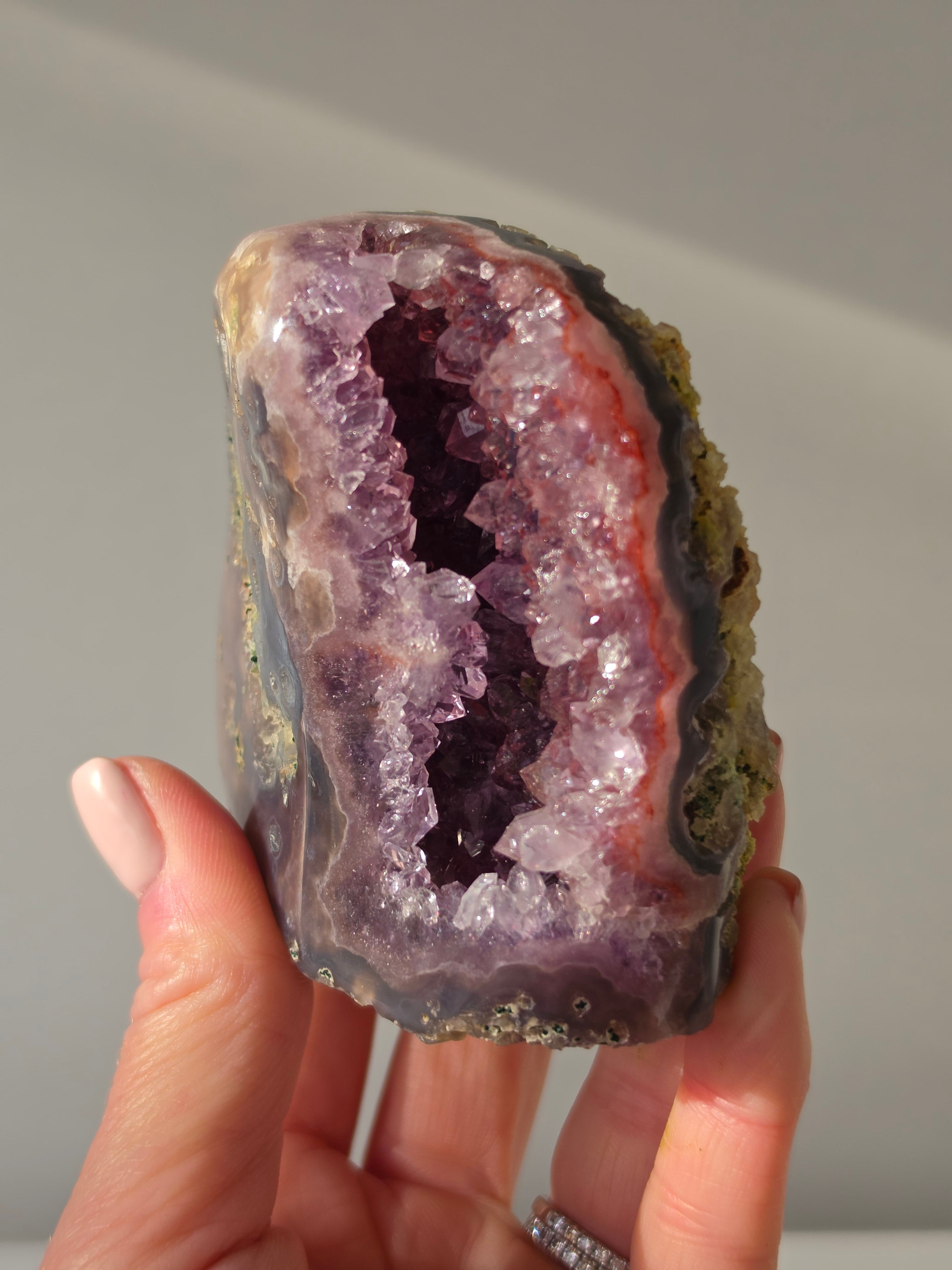 High-grade Brazilian Pink Amethyst cut base featuring a sparkling druzy crystal cavern, soft blush and lavender crystal points, natural agate banding in charcoal and rose tones, polished free-standing edges, and sourced from Rio Grande do Sul, Brazil.