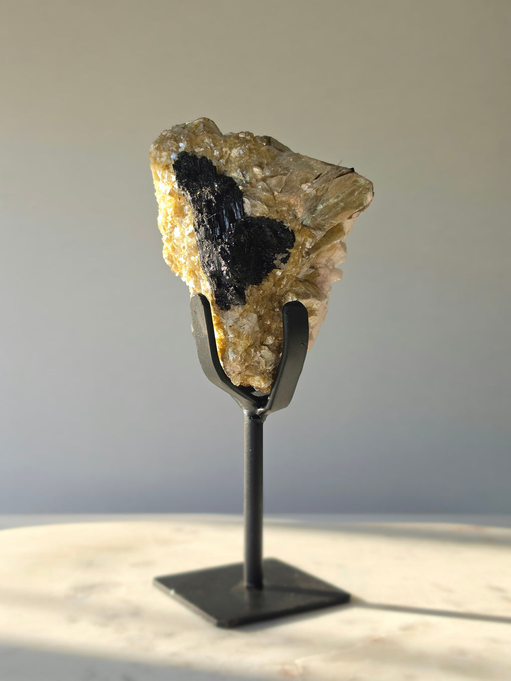 Golden Mica and Black Tourmaline mineral specimen with white Albite matrix displayed on a black metal stand, weighing 460g and measuring 16cm high including stand.