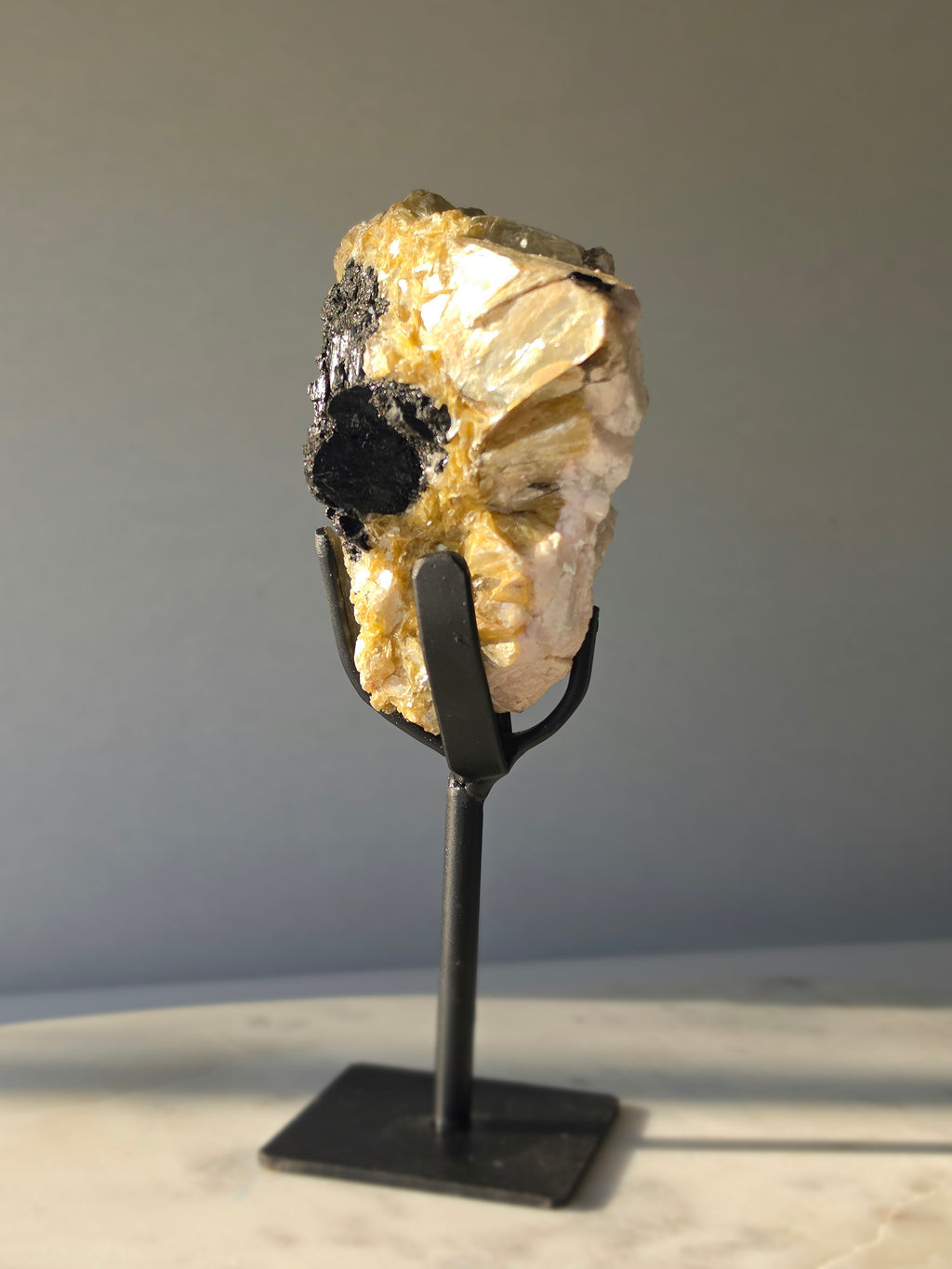 Golden Mica and Black Tourmaline mineral specimen with white Albite matrix displayed on a black metal stand, weighing 460g and measuring 16cm high including stand.