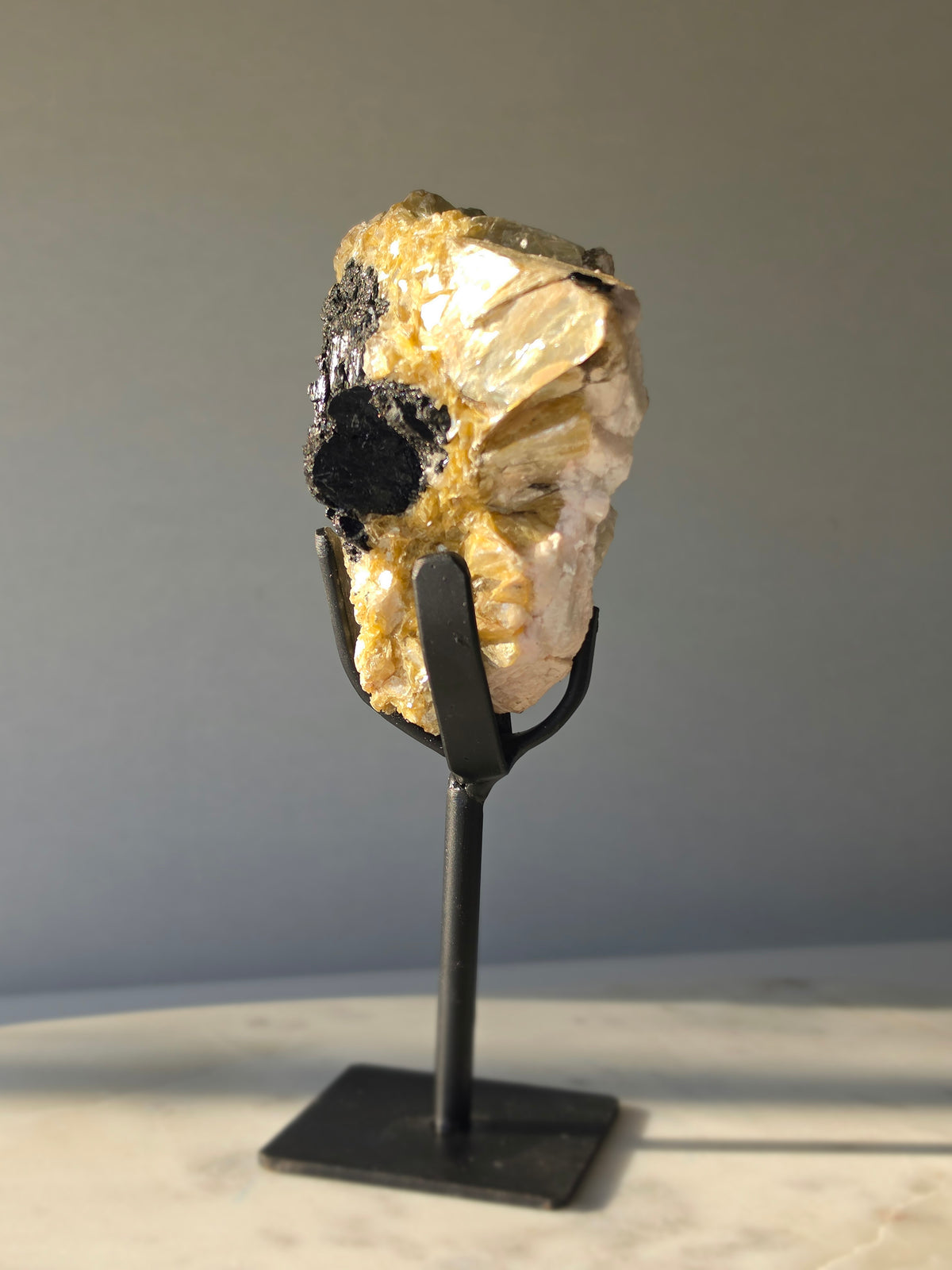 Golden Mica and Black Tourmaline mineral specimen with white Albite matrix displayed on a black metal stand, weighing 460g and measuring 16cm high including stand.