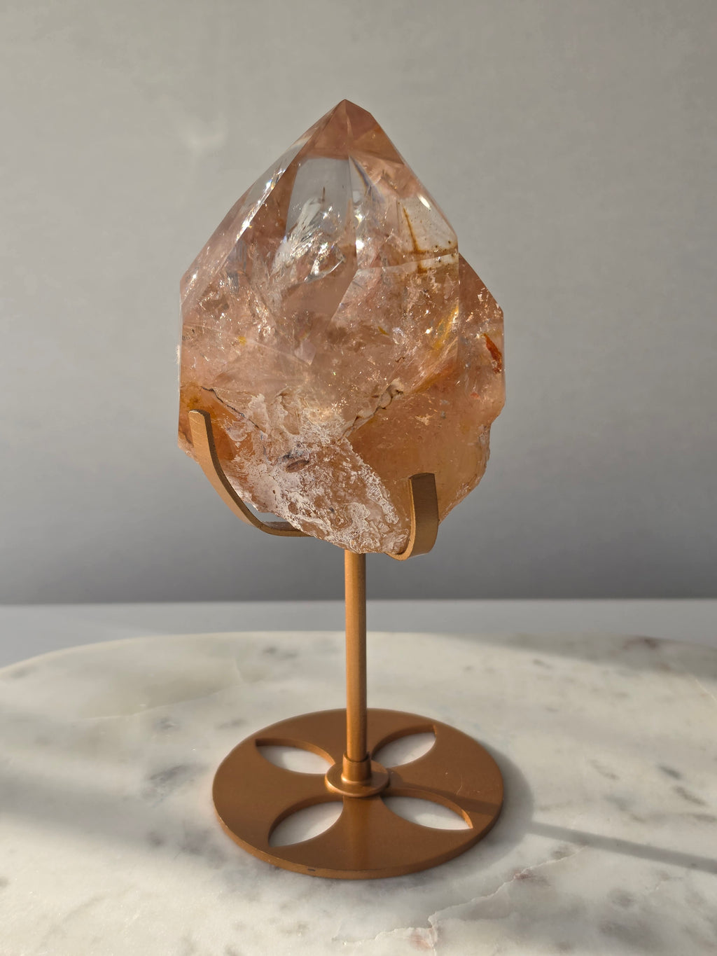 High-grade Nepalese Pink Himalayan Quartz statement piece, 697g and 19cm tall, featuring warm peachy-pink tones, translucent crystal formations and natural inclusions, displayed on a gold stand.