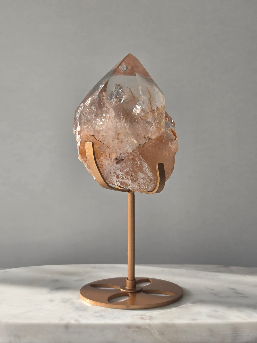 High-grade Nepalese Pink Himalayan Quartz statement piece, 697g and 19cm tall, featuring warm peachy-pink tones, translucent crystal formations and natural inclusions, displayed on a gold stand.
