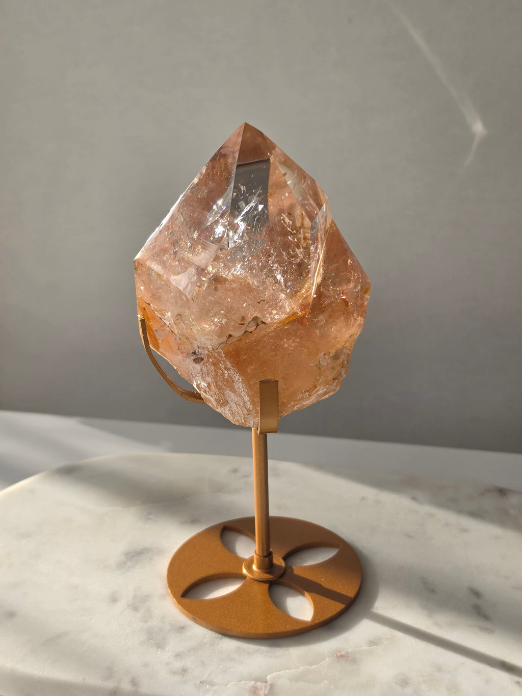 High-grade Nepalese Pink Himalayan Quartz statement piece, 697g and 19cm tall, featuring warm peachy-pink tones, translucent crystal formations and natural inclusions, displayed on a gold stand.