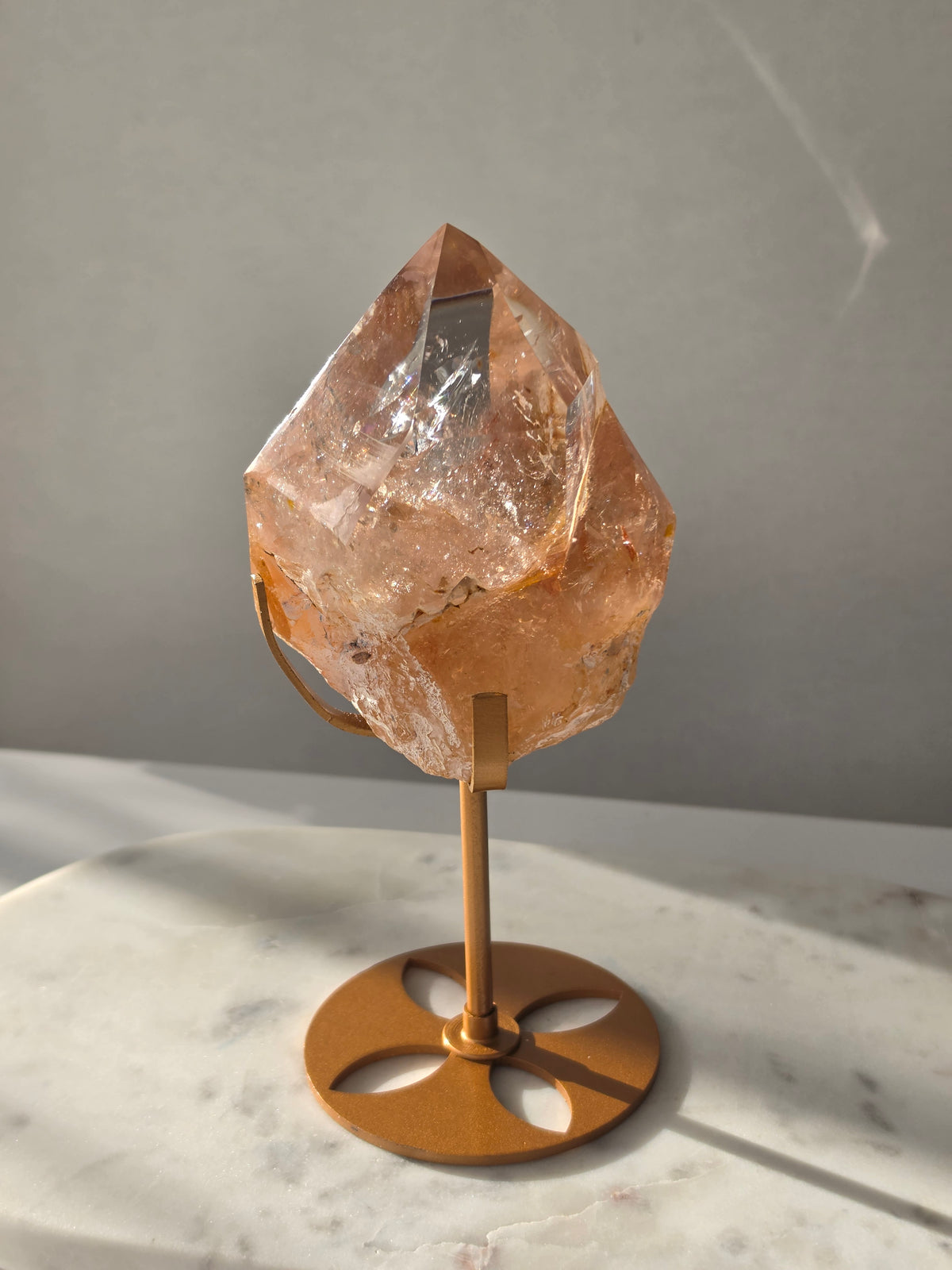 High-grade Nepalese Pink Himalayan Quartz statement piece, 697g and 19cm tall, featuring warm peachy-pink tones, translucent crystal formations and natural inclusions, displayed on a gold stand.