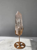 High-grade Nepalese Pink Himalayan Quartz statement point, 626g and 25.5cm tall, featuring soft blush pink tones, natural inclusions and translucent crystal formations, displayed on a gold stand by Stone & Bloom Co.