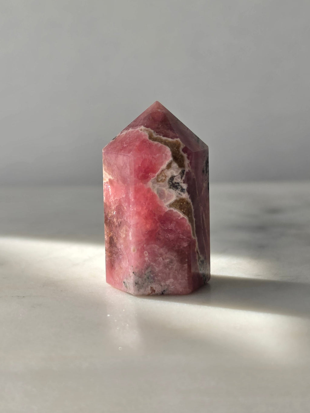 Polished Argentine Rhodochrosite crystal point with deep raspberry pink colour and intricate cream, blush and dark mineral banding, 37g, 4cm.