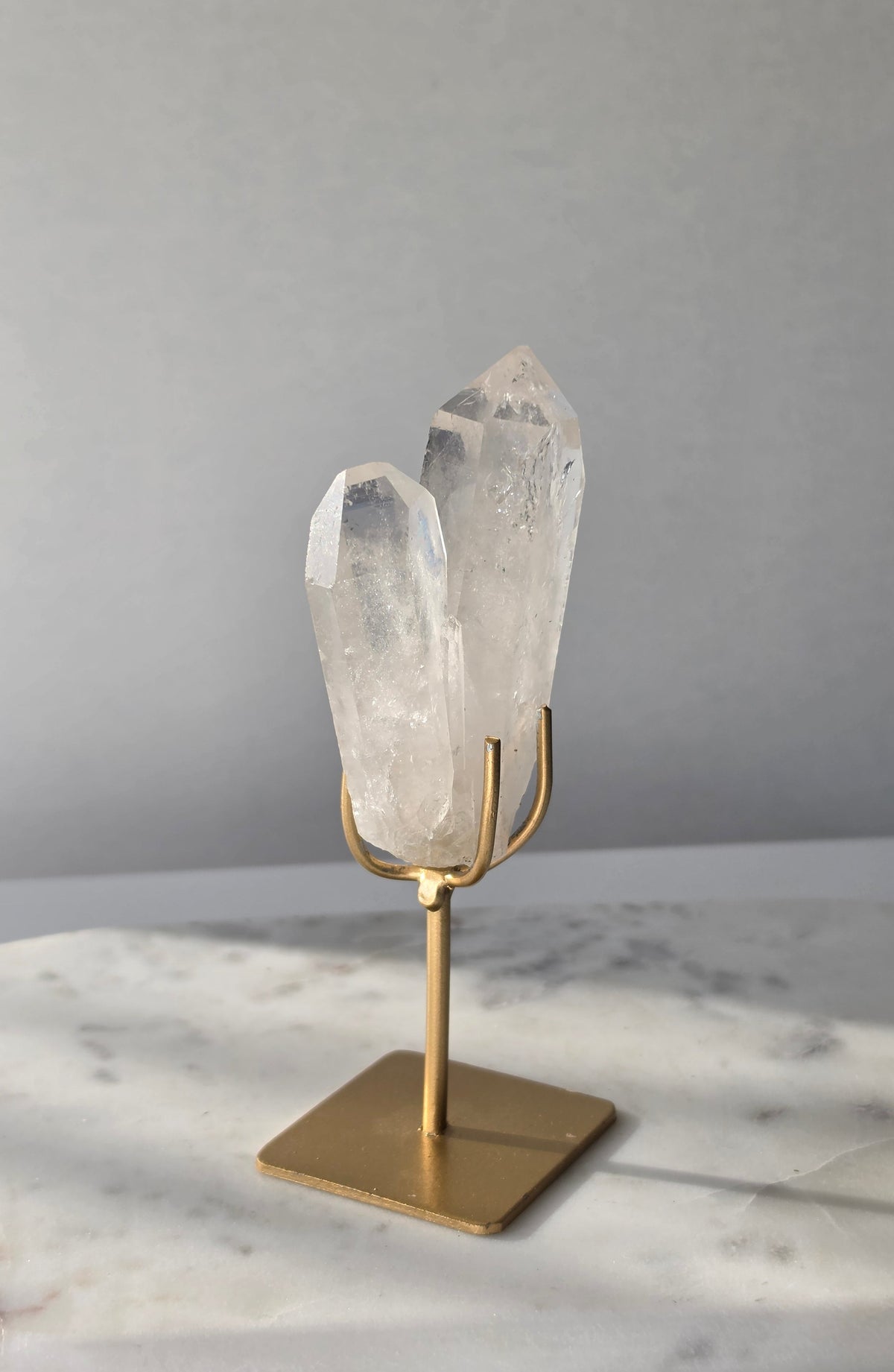 Clear Quartz Lemurian crystal on gold stand featuring exceptional clarity, natural rainbow inclusions, internal formations and striking crystal points