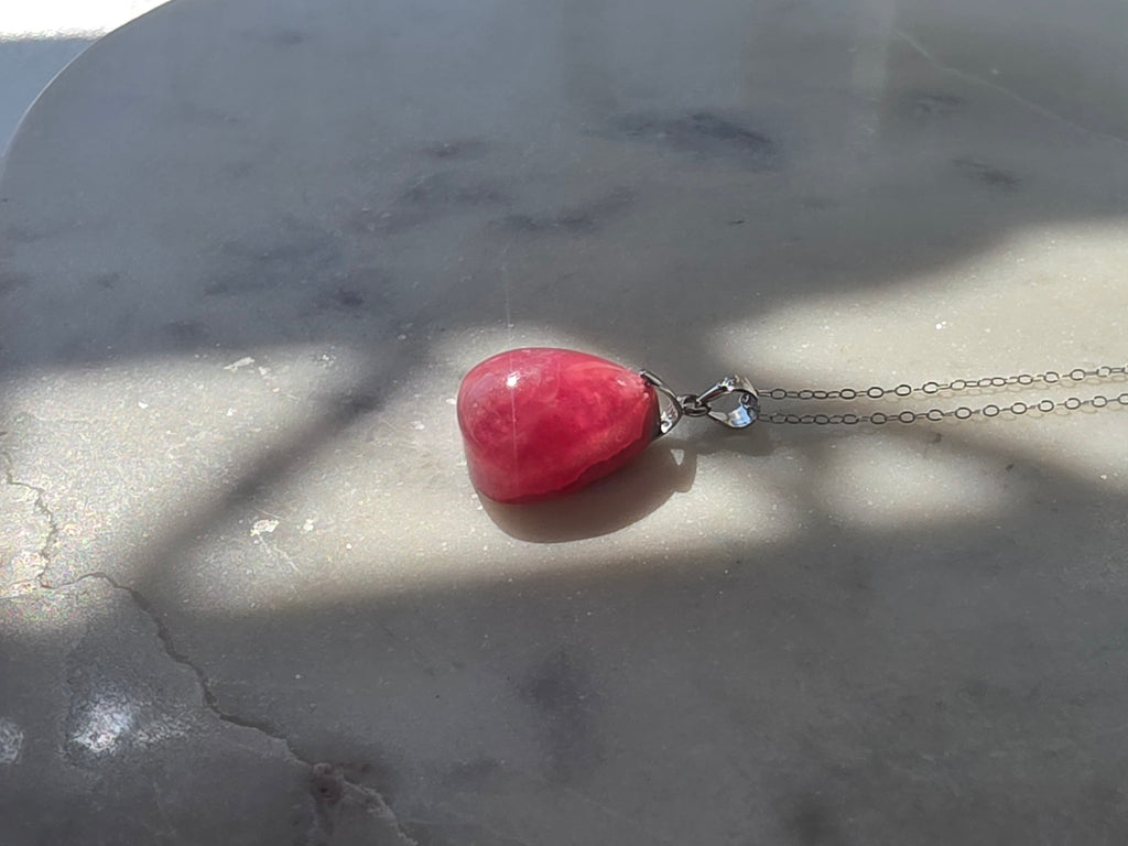 Natural Rhodochrosite teardrop pendant in 925 sterling silver with matching silver chain, featuring vibrant pink tones and unique natural patterns
