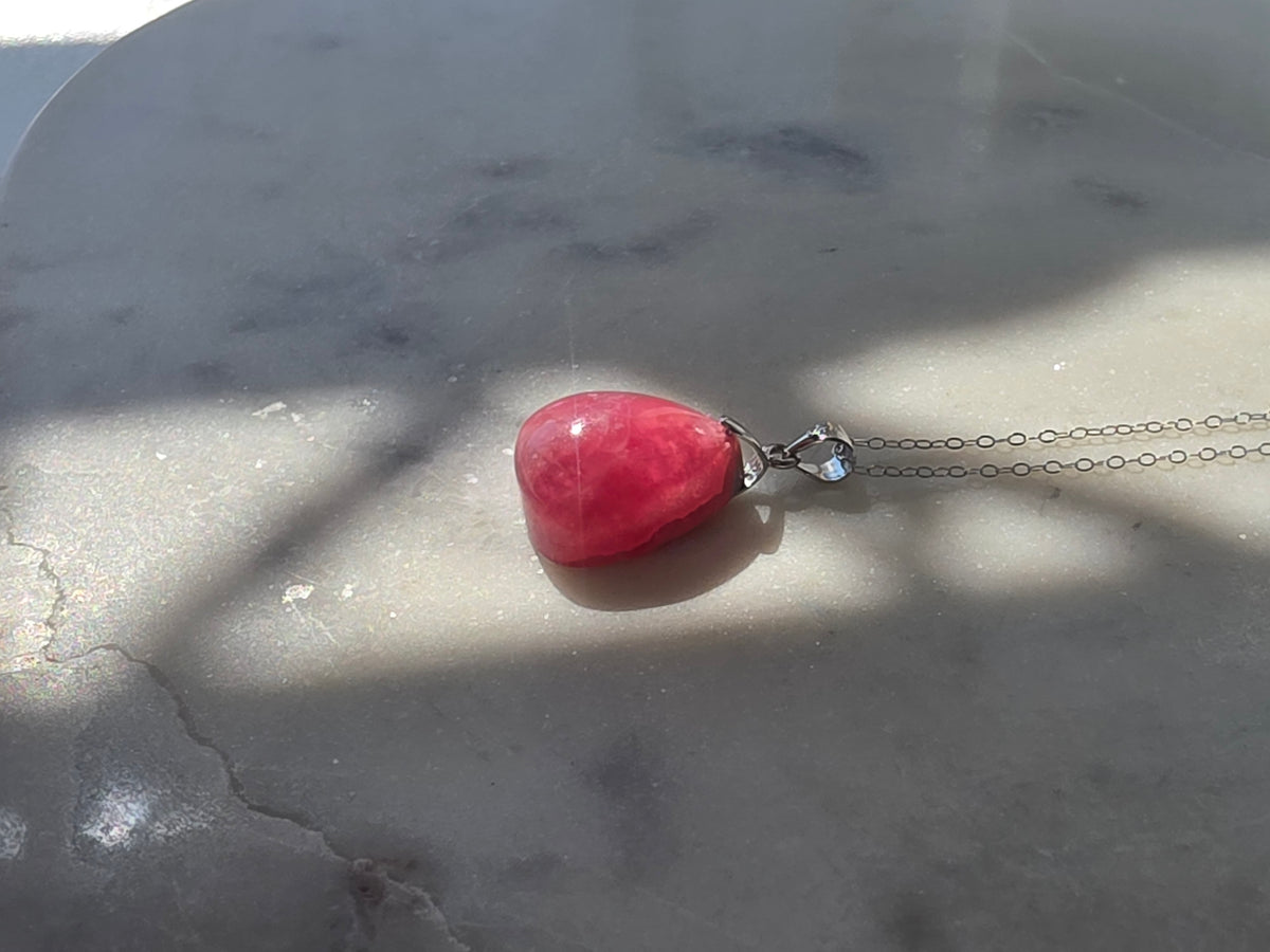 Natural Rhodochrosite teardrop pendant in 925 sterling silver with matching silver chain, featuring vibrant pink tones and unique natural patterns