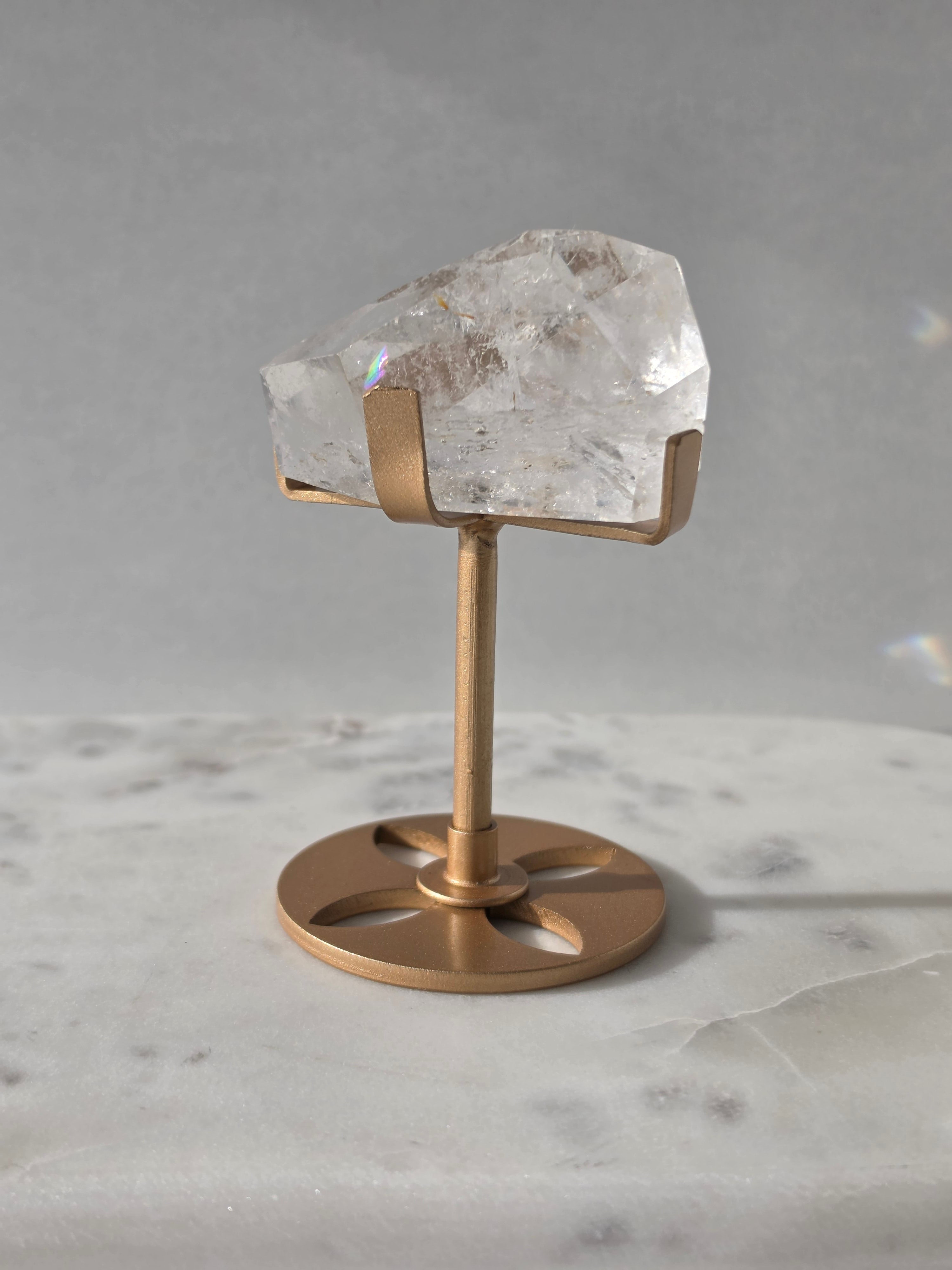 Clear Quartz freeform crystal with natural internal inclusions and luminous clarity, displayed on an elegant gold-finished stand.