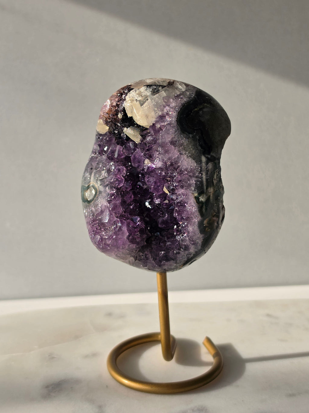 Natural Amethyst Stalactite with Calcite inclusions and blush red tones on a luxury gold display stand