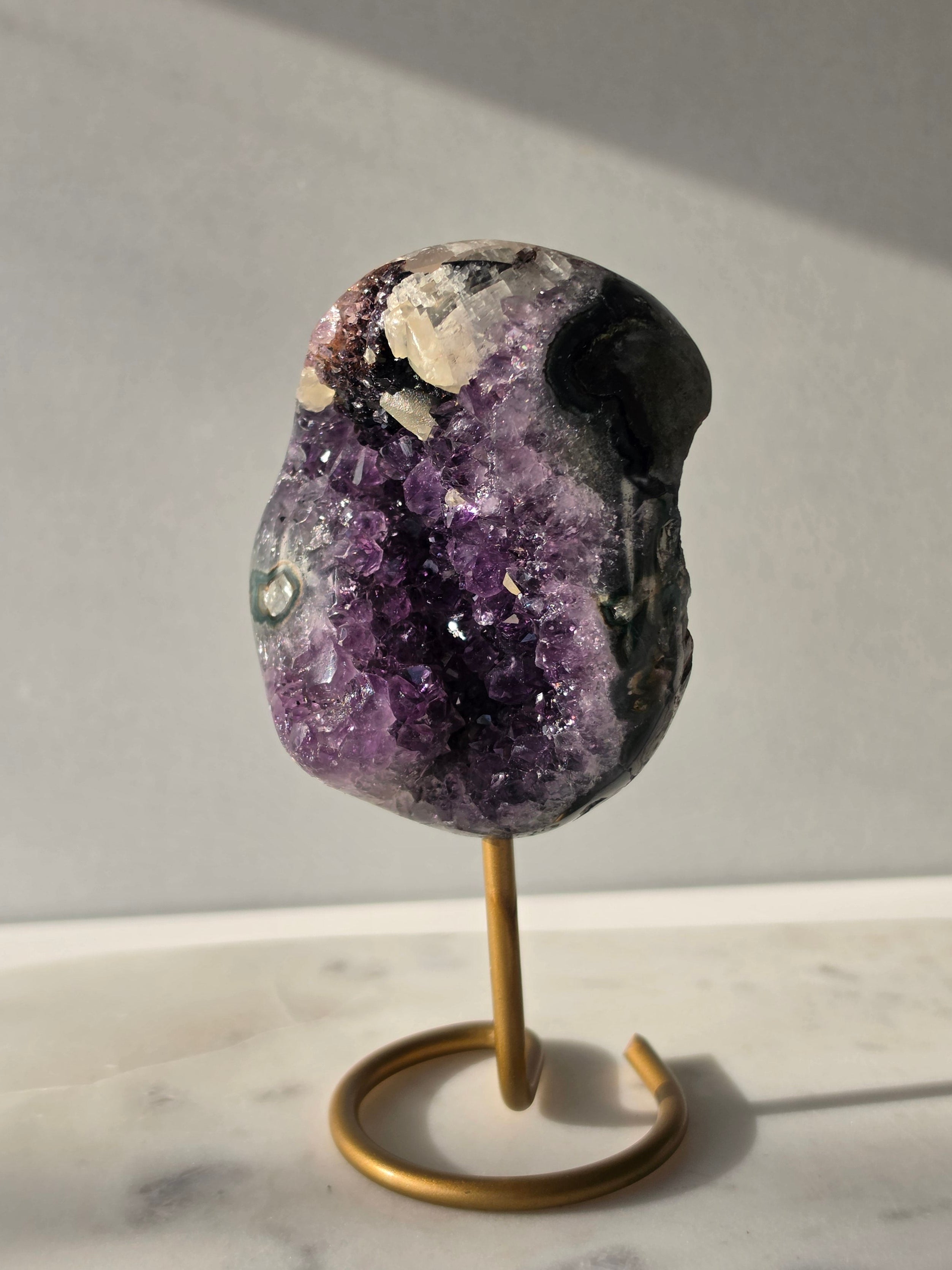 Natural Amethyst Stalactite with Calcite inclusions and blush red tones on a luxury gold display stand