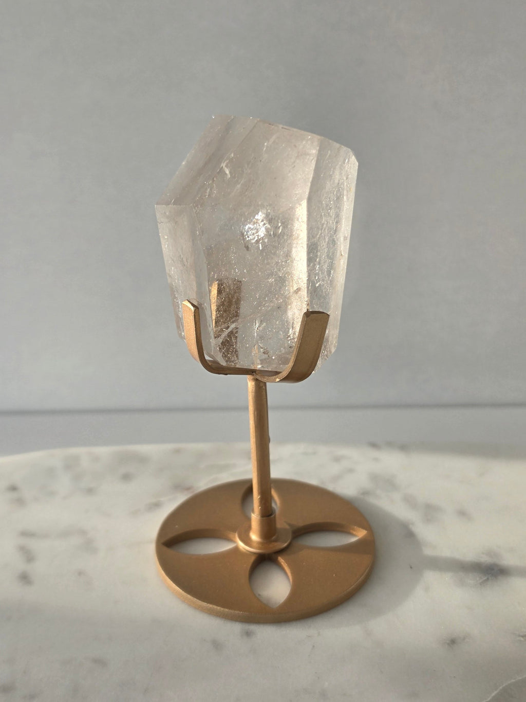 Clear Quartz freeform crystal with subtle smoky-grey translucence, natural internal inclusions and luminous clarity, displayed on an elegant gold-finished stand.