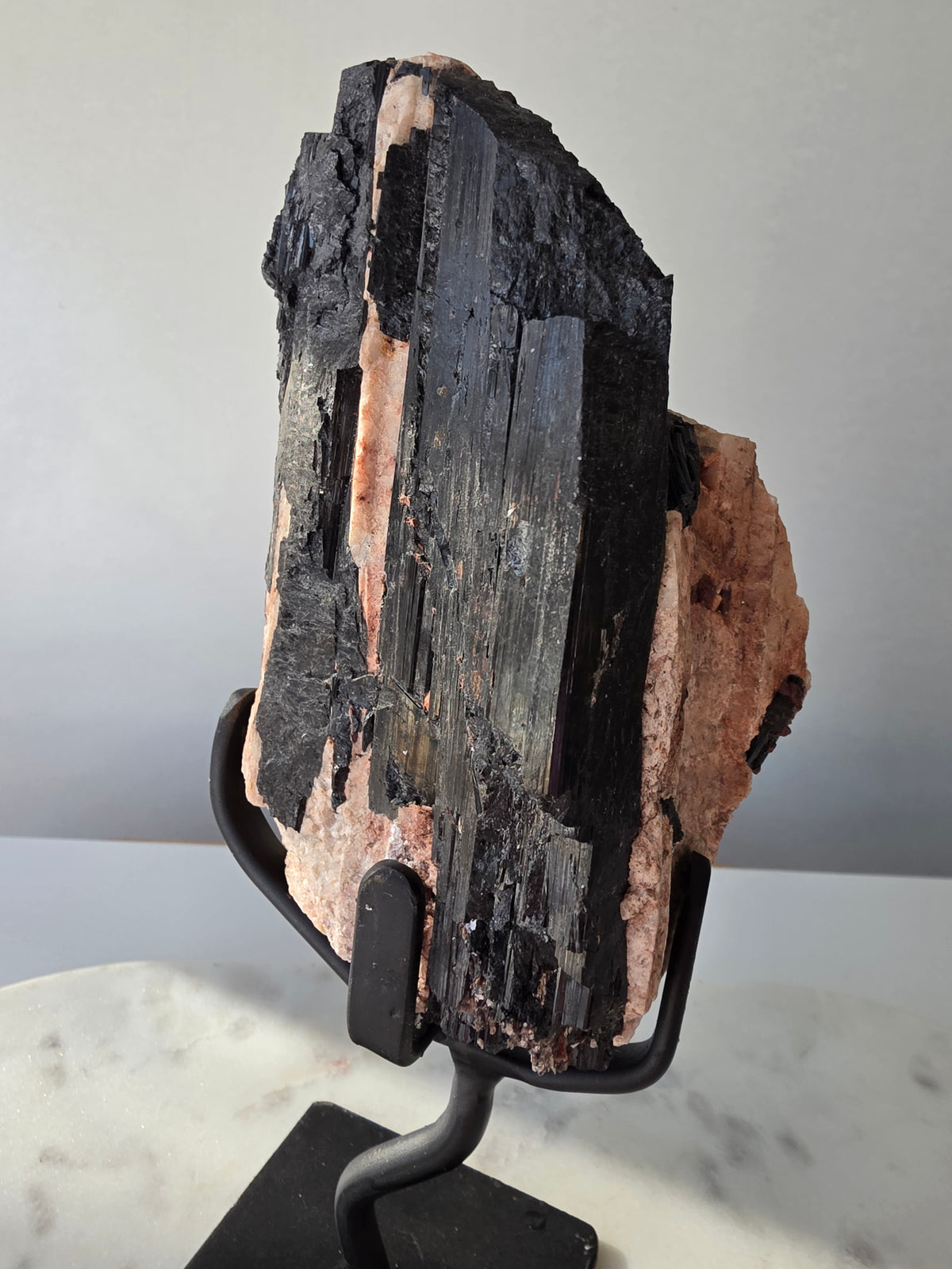 Black Tourmaline on Feldspar matrix from Brazil featuring naturally formed black crystals, contrasting pale matrix, black display stand, 910g, 19.5 × 6.5cm.