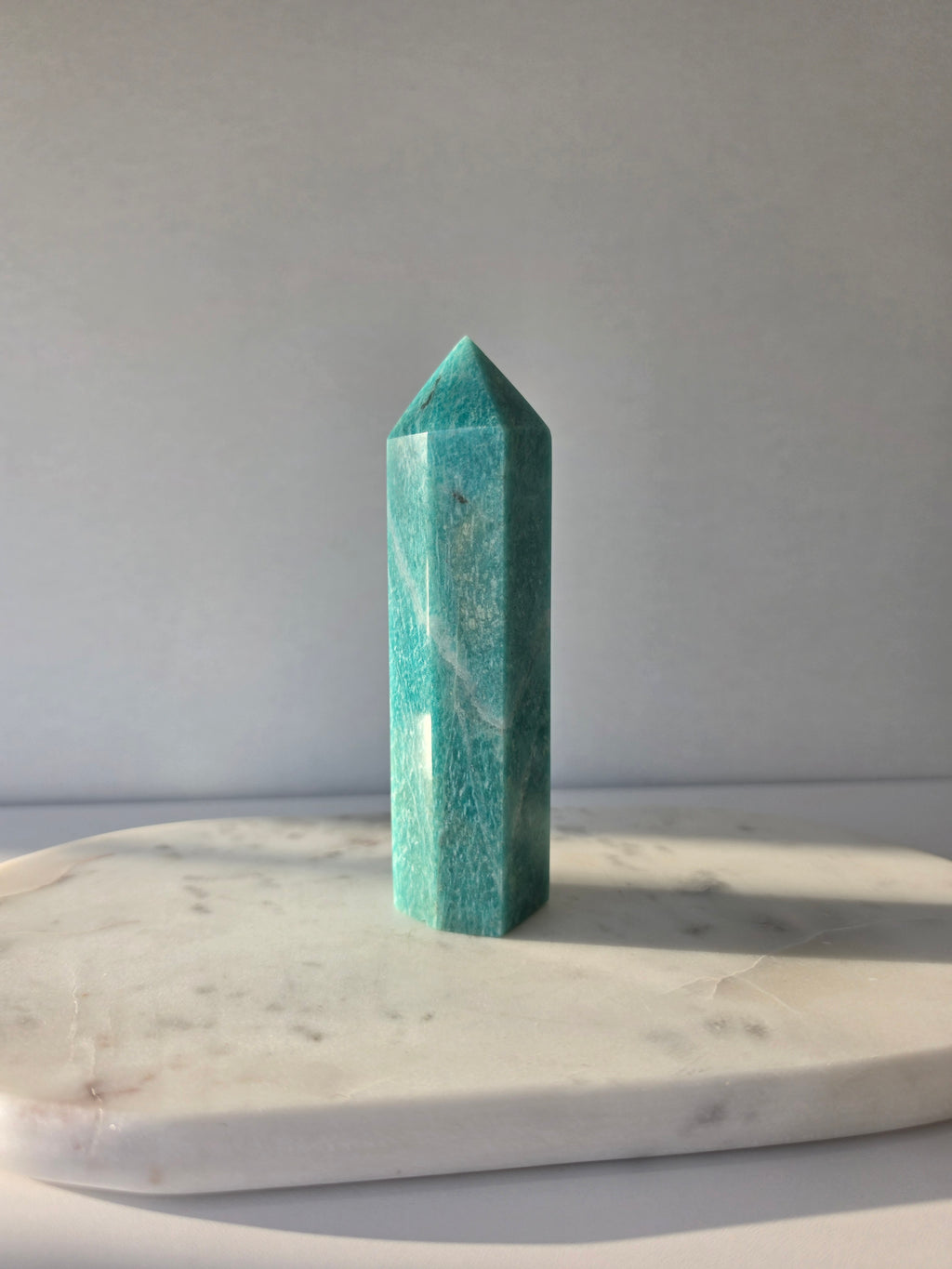 Natural Amazonite tower in soft mint and sea-green tones with subtle blue-green variations, polished geometric point and delicate natural inclusions, displayed as a luxury crystal statement piece.