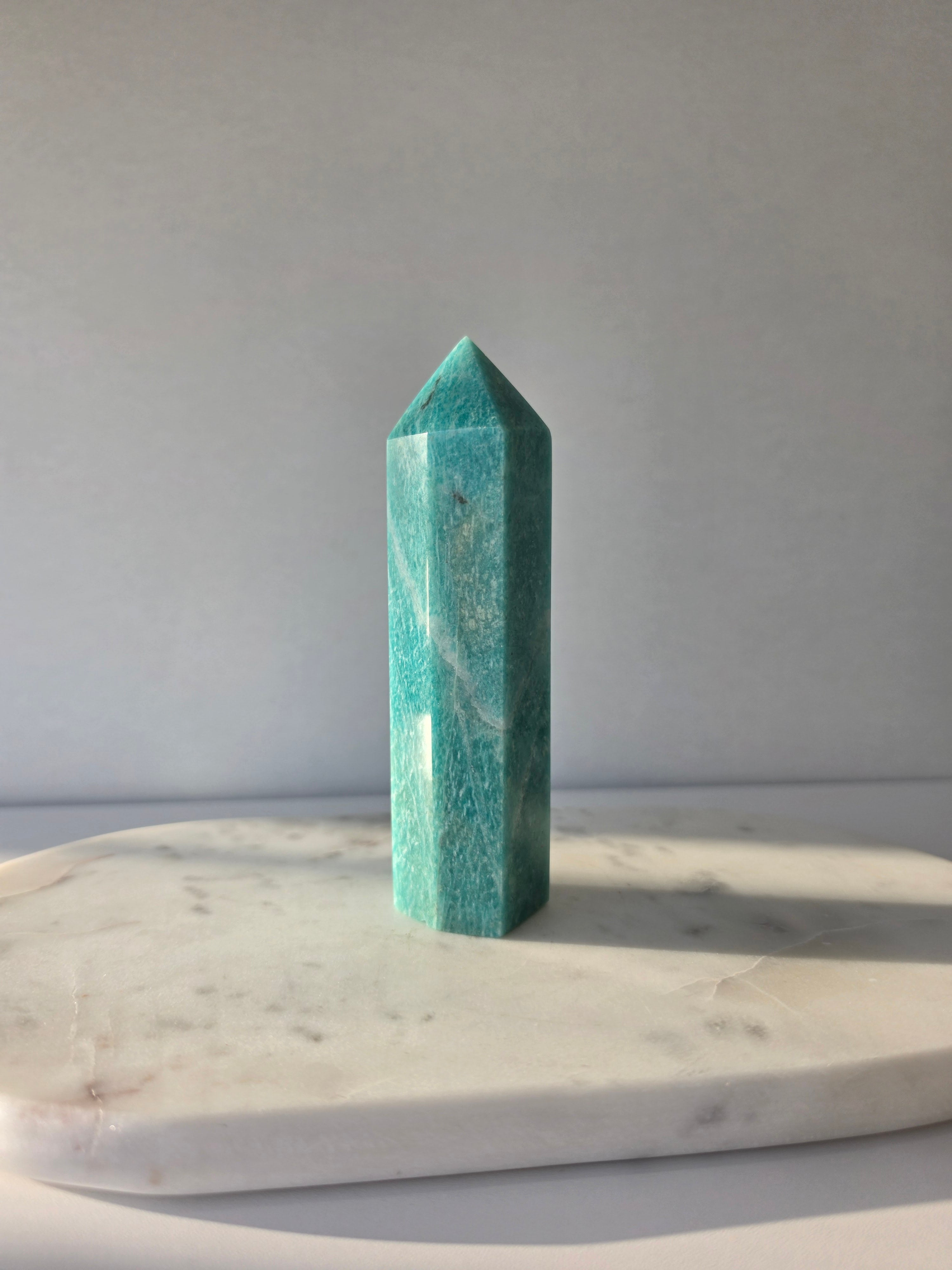 Natural Amazonite tower in soft mint and sea-green tones with subtle blue-green variations, polished geometric point and delicate natural inclusions, displayed as a luxury crystal statement piece.