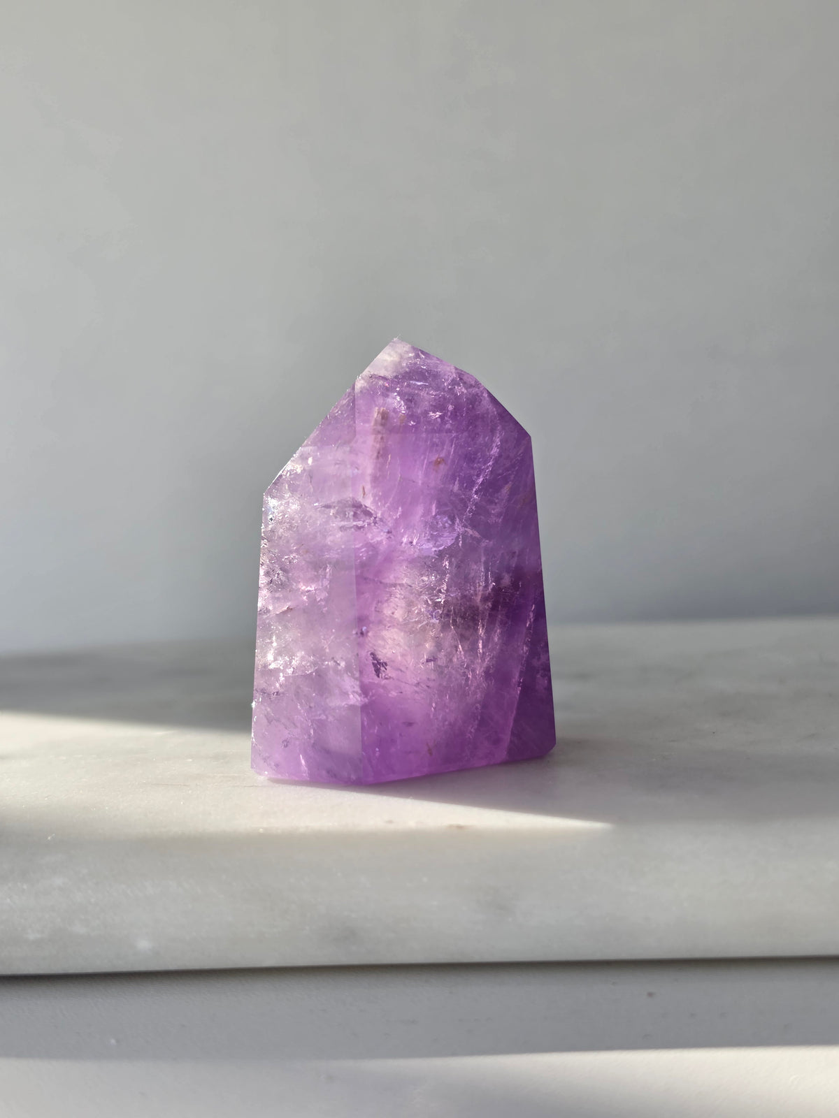 High clarity purple Amethyst tower from Brazil featuring rich violet and lavender hues, translucent crystal formations and polished reflective facets.