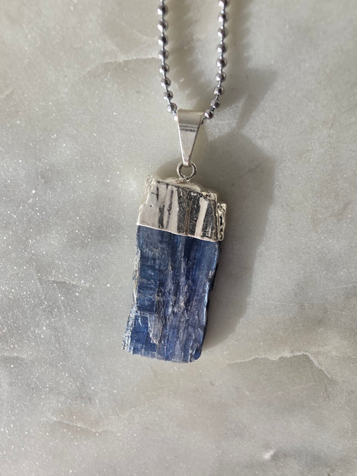 Natural Blue Kyanite raw crystal pendant with silver-plated cap from the Stone & Bloom Raw Luxe Collection, featuring deep blue tones and natural crystal texture.