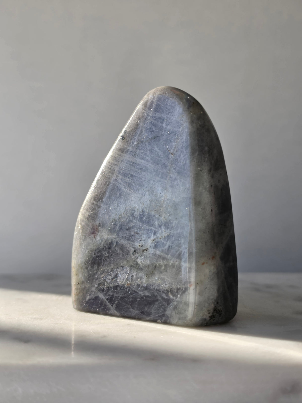 259g polished Labradorite cut base with smoky grey and charcoal colouring, natural silvery patterns and blue turquoise iridescence on the front.