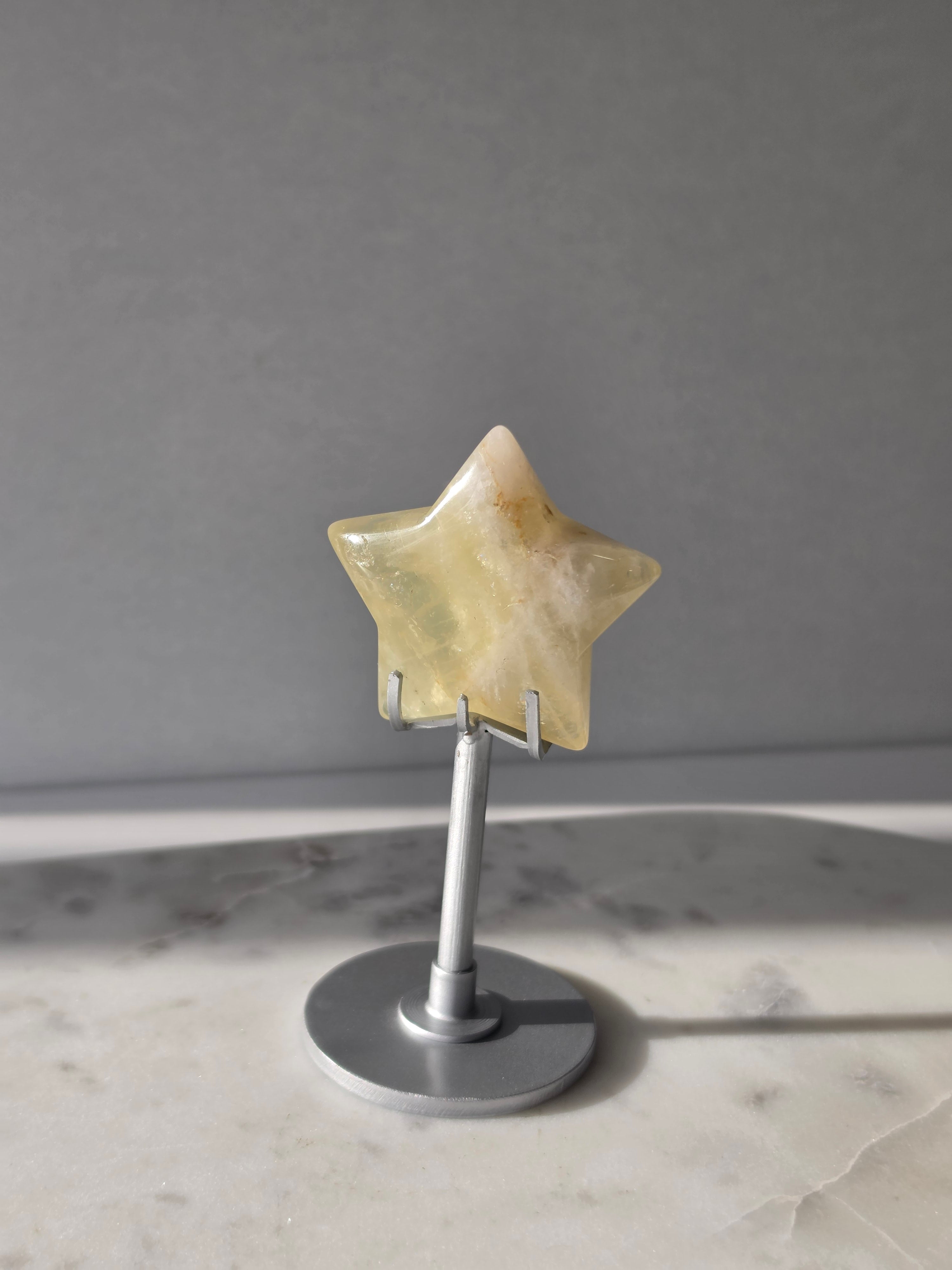 Natural citrine crystal star on a silver stand, featuring translucent golden tones and unique crystal formations, Stone & Bloom statement decor