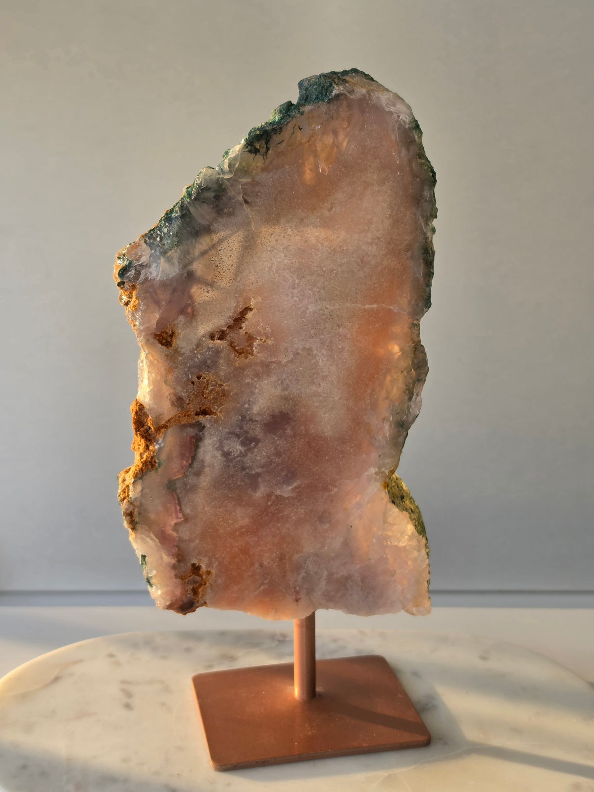 Back Shot of Large Brazilian Pink Amethyst slice on display stand with translucent Quartz, sparkling crystalline texture, earthy brown Jasper features and deep green natural matrix