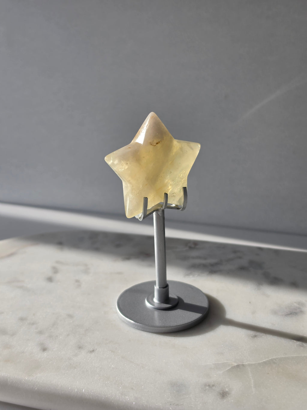 Natural citrine crystal star on a silver stand, featuring translucent golden tones and unique crystal formations, Stone & Bloom statement decor