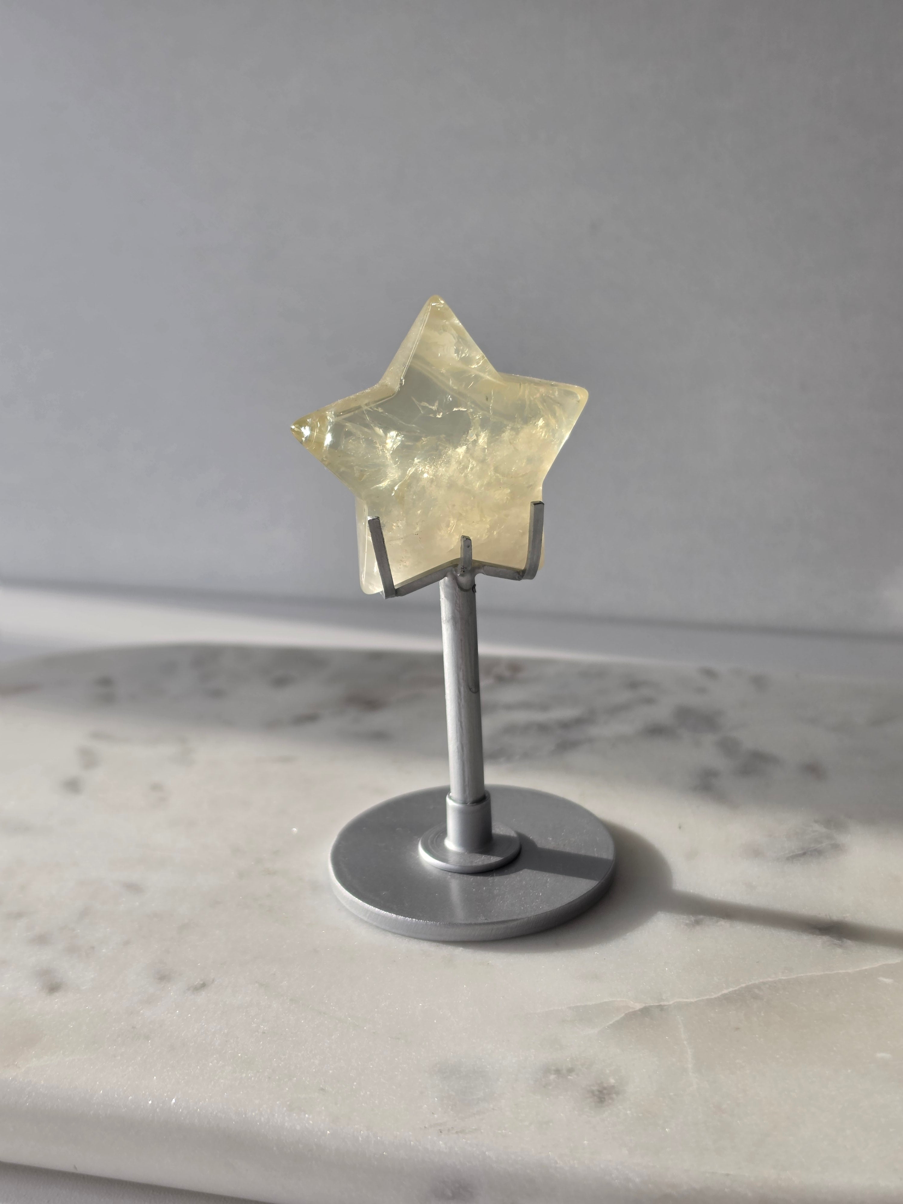 Natural citrine crystal star on a silver stand, featuring translucent golden tones and unique crystal formations, Stone & Bloom statement decor