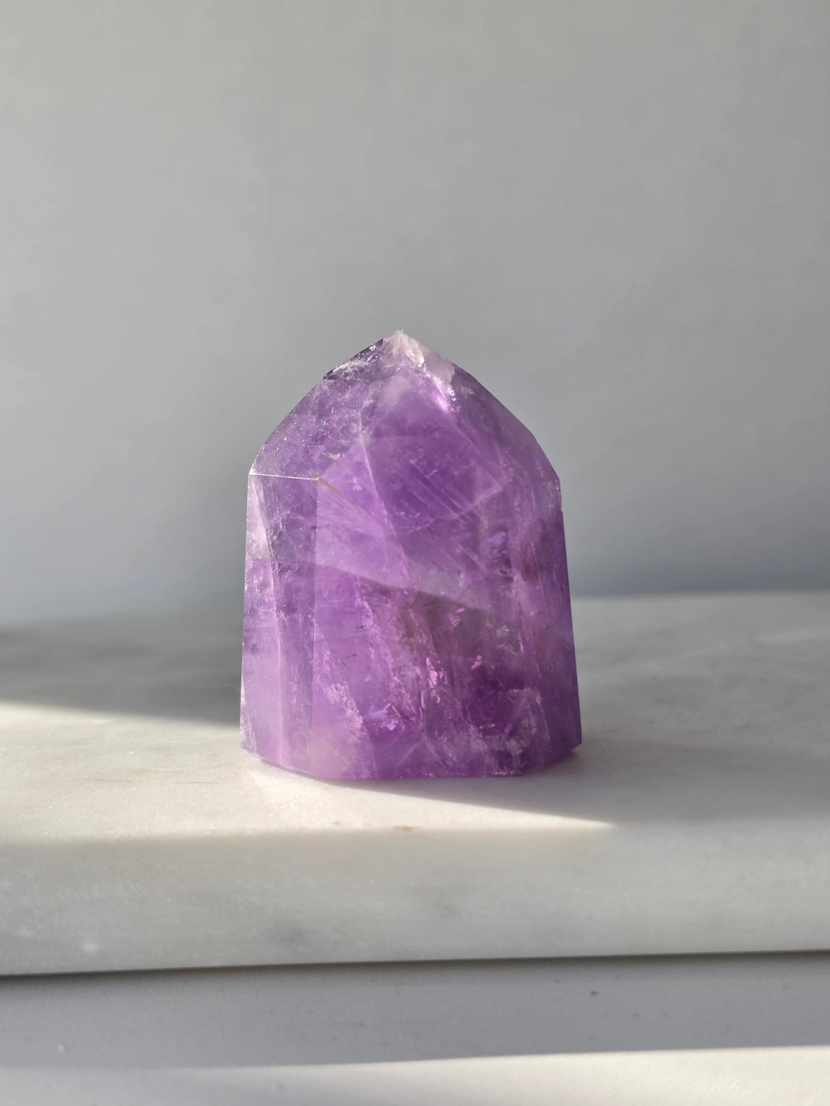 High clarity purple Amethyst tower from Brazil featuring rich violet and lavender hues, translucent crystal formations and polished reflective facets.